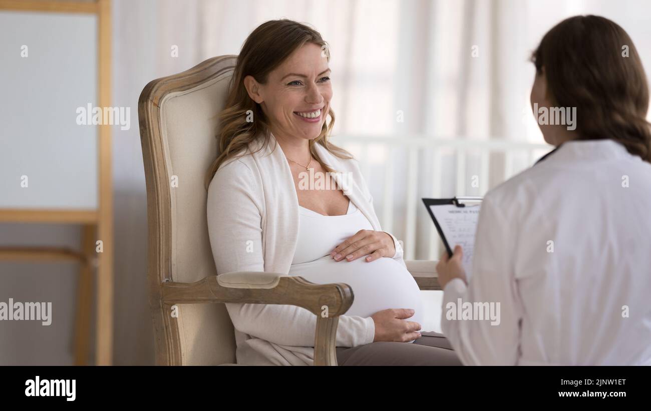 La giovane paziente incinta risponde alle domande del ginecologo durante la visita Foto Stock