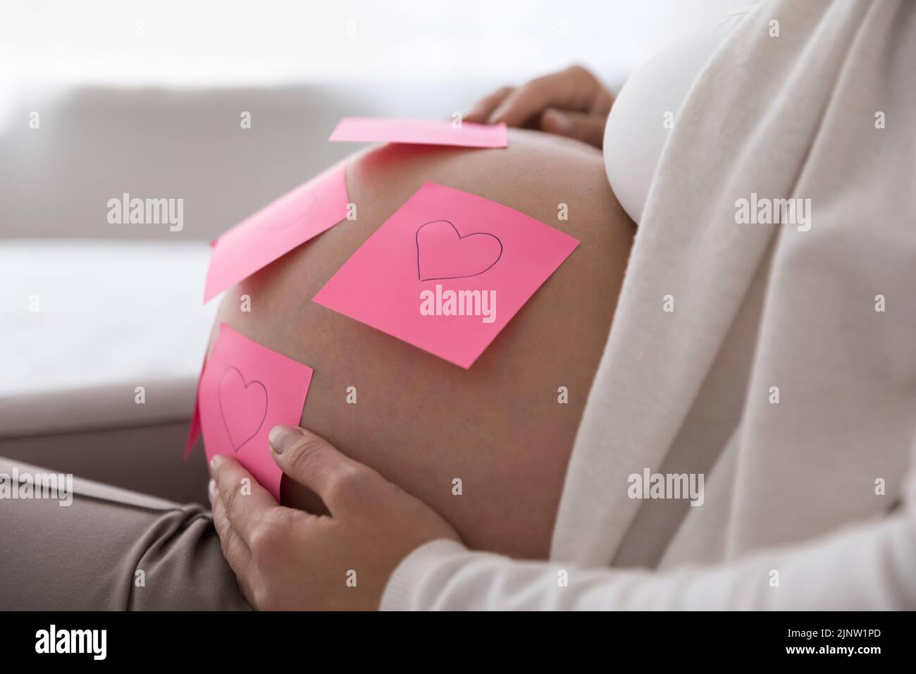 Note adesive con i cuori attaccati sul ventre della donna incinta Foto Stock