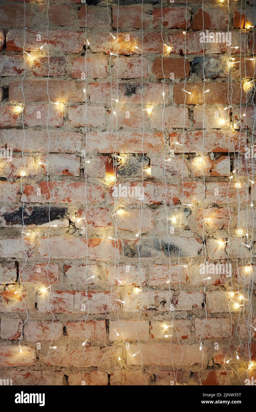 Muro di mattoni con sfondo di Natale. Luci a LED sulla struttura in muratura Foto Stock