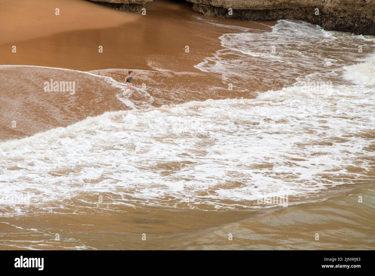 Bambini che giocano con le onde dell'oceano sulla grande spiaggia Foto Stock