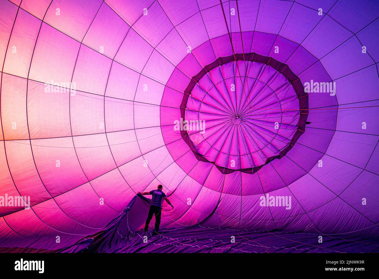 Un pilota di mongolfiera controlla il rigging durante i controlli di gonfiaggio pre-volo durante la Bristol International Balloon Fiesta 2022. Data immagine: Domenica 14 agosto 2022. Foto Stock