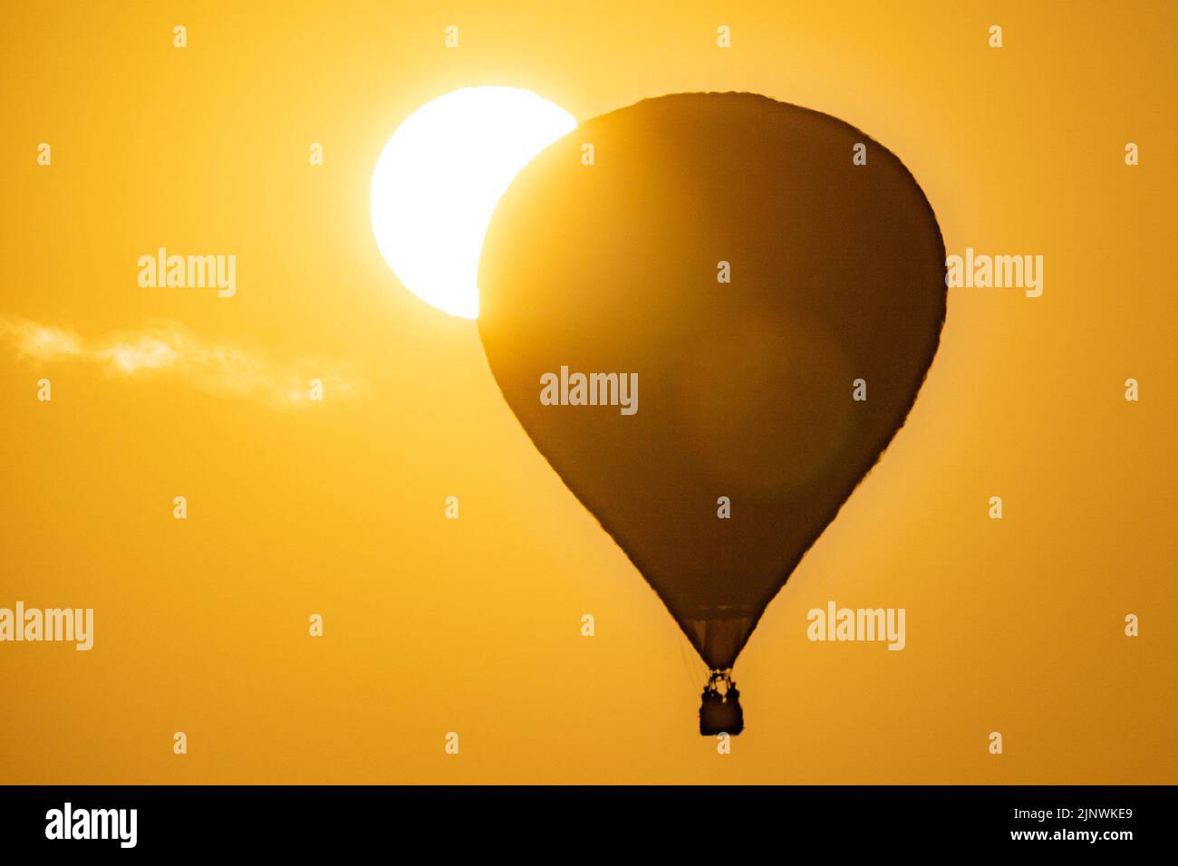 Una mongolfiera passa accanto al sole mentre vola sopra il North Somerset alla luce del sole della mattina presto, durante l'ascesa di massa della Bristol International Balloon Fiesta 2022. Data immagine: Domenica 14 agosto 2022. Foto Stock