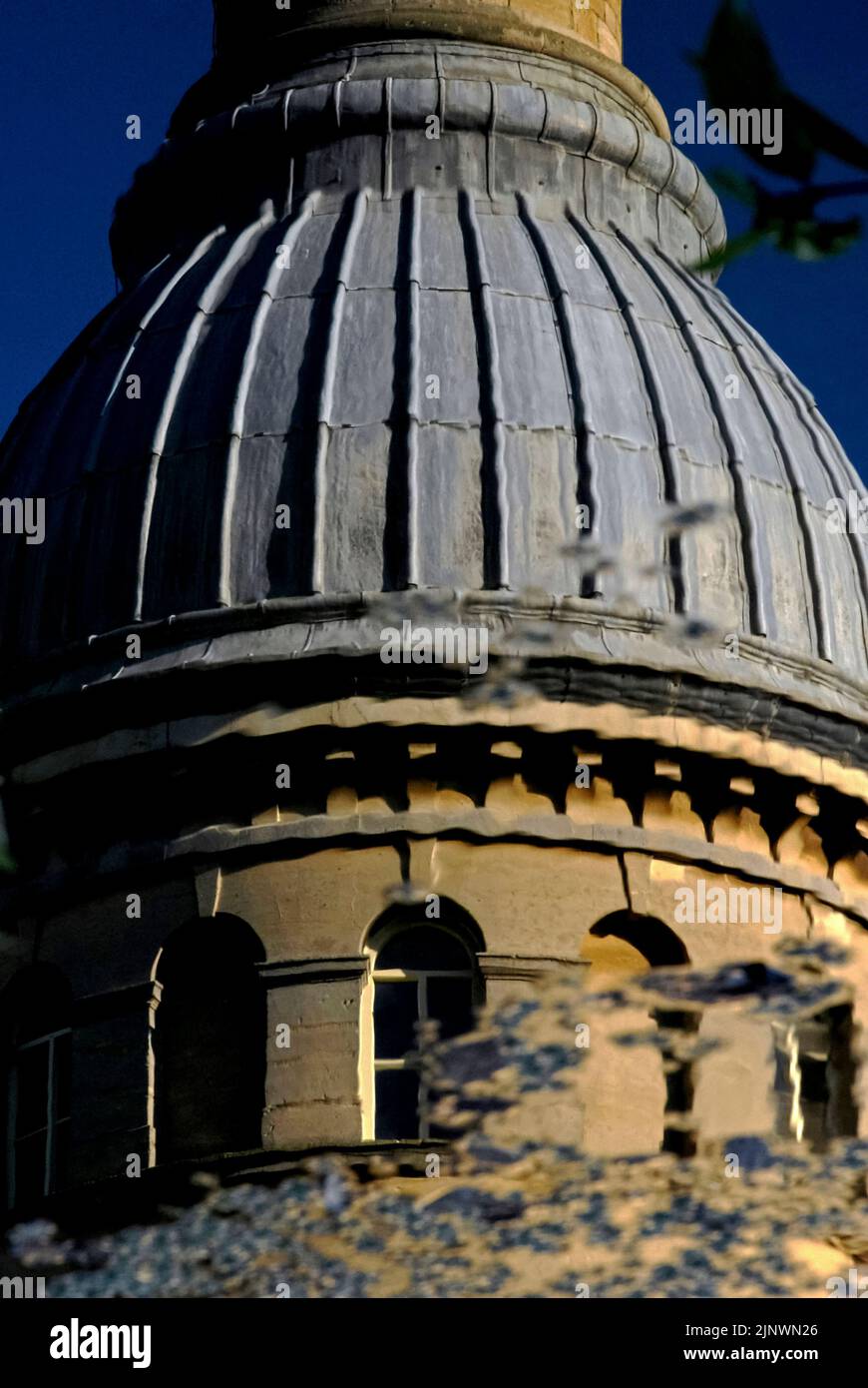 Una leggera brezza ruba la superficie del lago prima dell'ex Bliss Tweed Mill a Chipping Norton, Oxfordshire, Inghilterra, Regno Unito, offuscando le linee della sua torre dell'orologio circolare, ricoperta da una caratteristica cupola rivestita in piombo e da un'elegante ciminiera. Il mulino è stato chiuso nel 1980 ma ora è diviso in appartamenti di lusso. Foto Stock