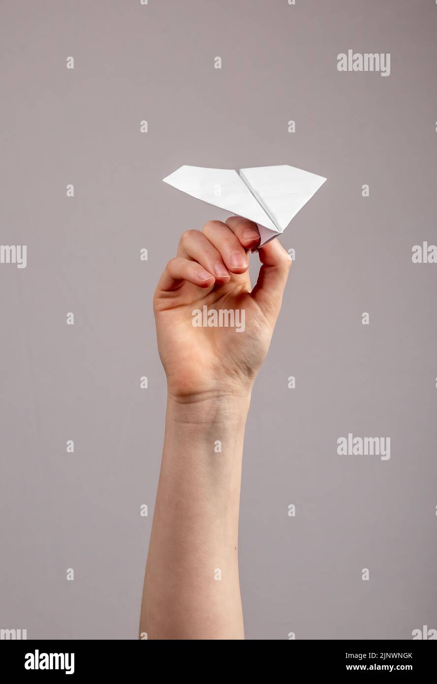 Aereo aereo di carta origami giocattolo in mani primo piano. Concetti di viaggio aereo o di invio di messaggi notizie. Foto Stock