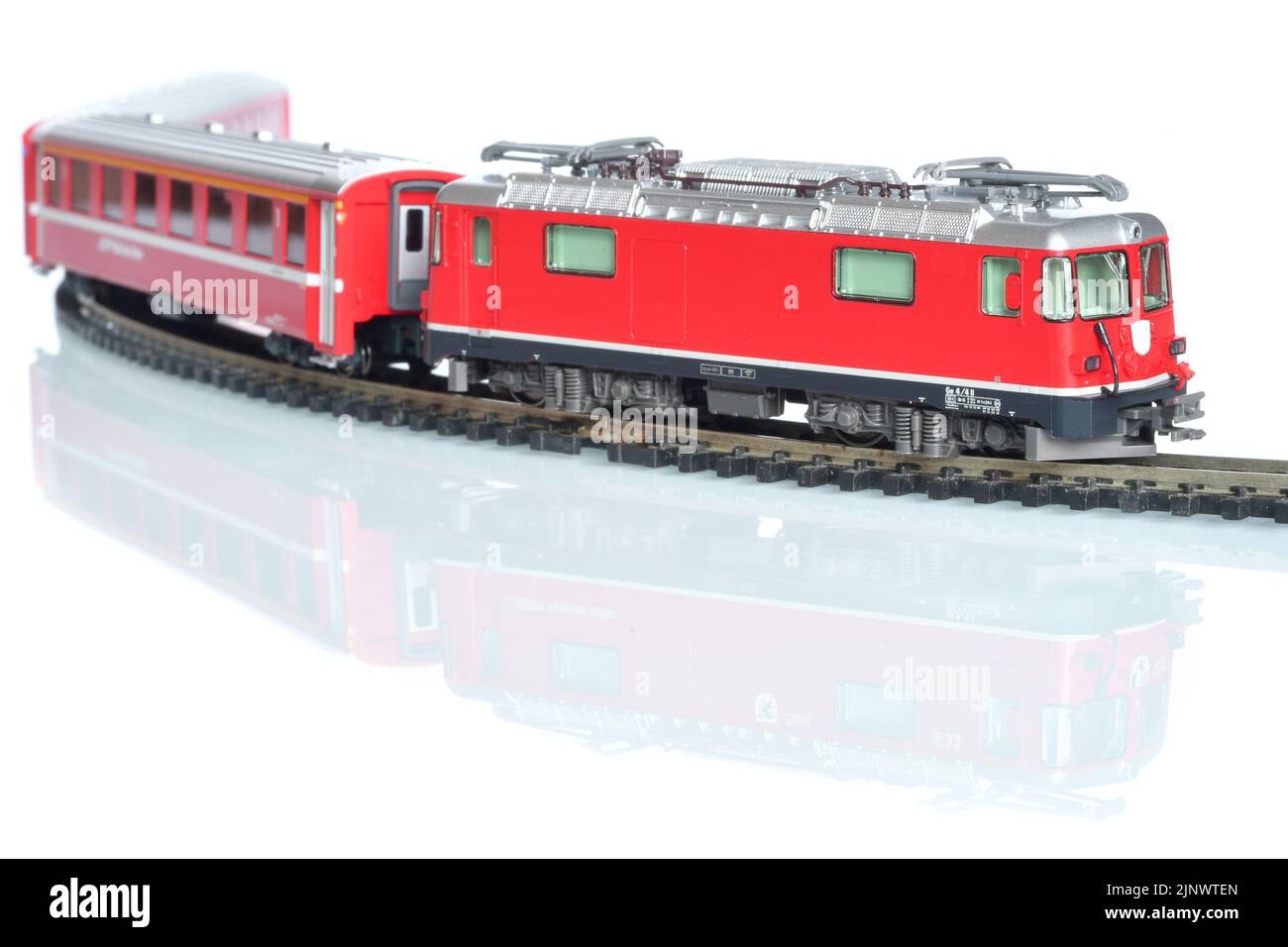 Modello giocattolo in scala di treno rosso isolato su sfondo bianco riflettente Foto Stock