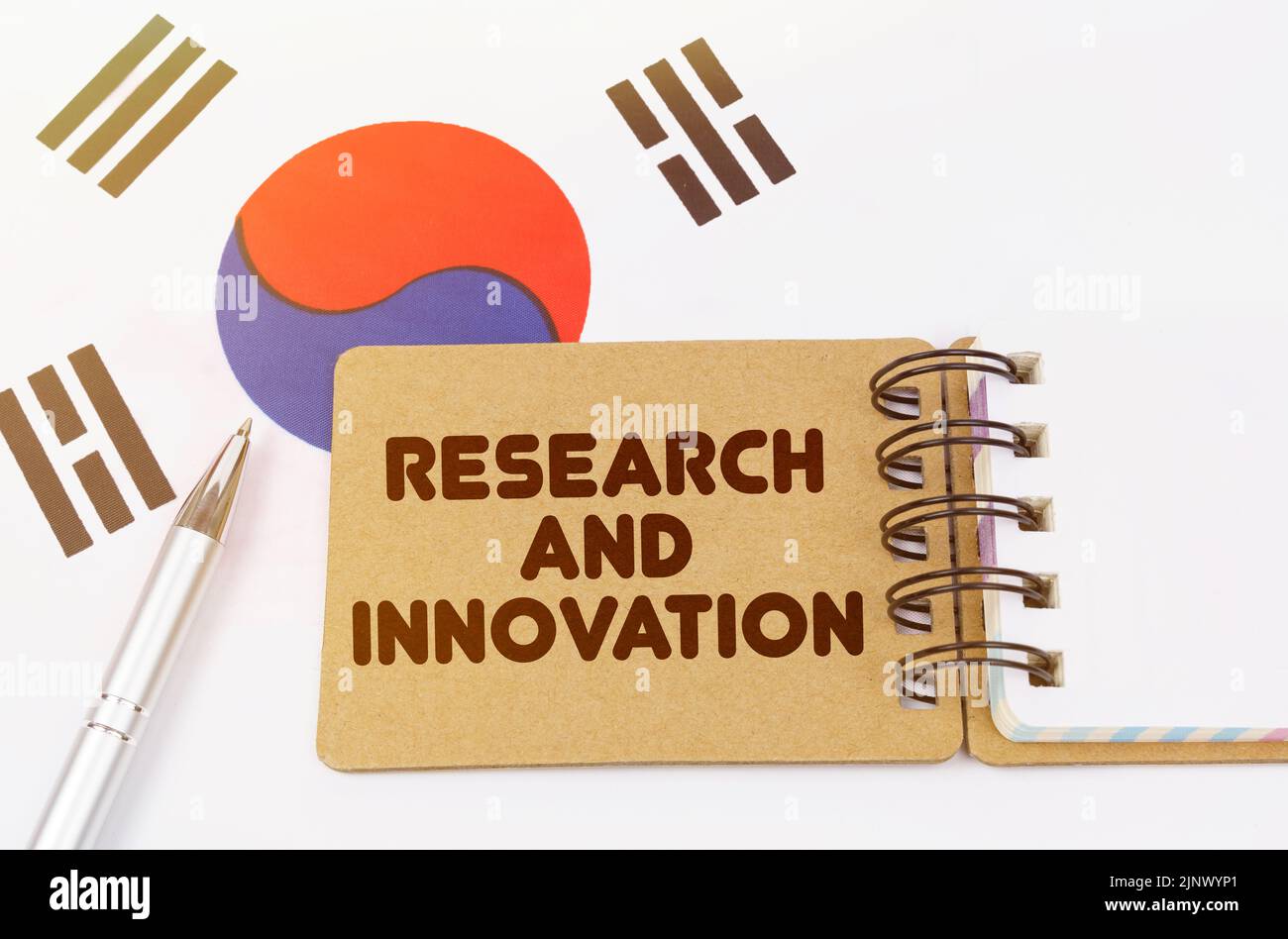 Concetto di economia nazionale. Sulla bandiera della Corea del Sud si trova un quaderno con l'iscrizione Ricerca e innovazione Foto Stock