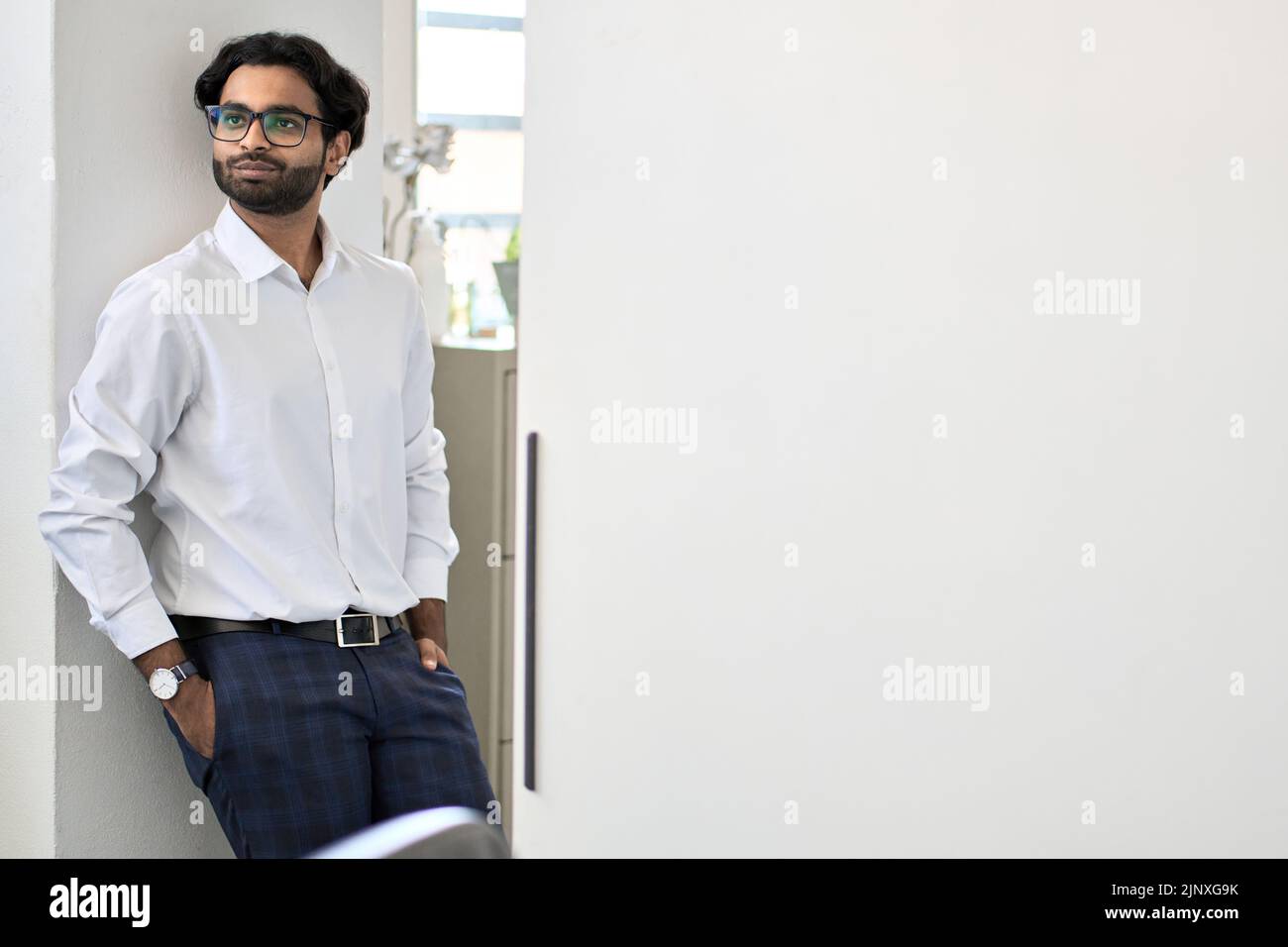 Elegante e ricco giovane uomo indiano di affari di successo in piedi in ufficio. Foto Stock