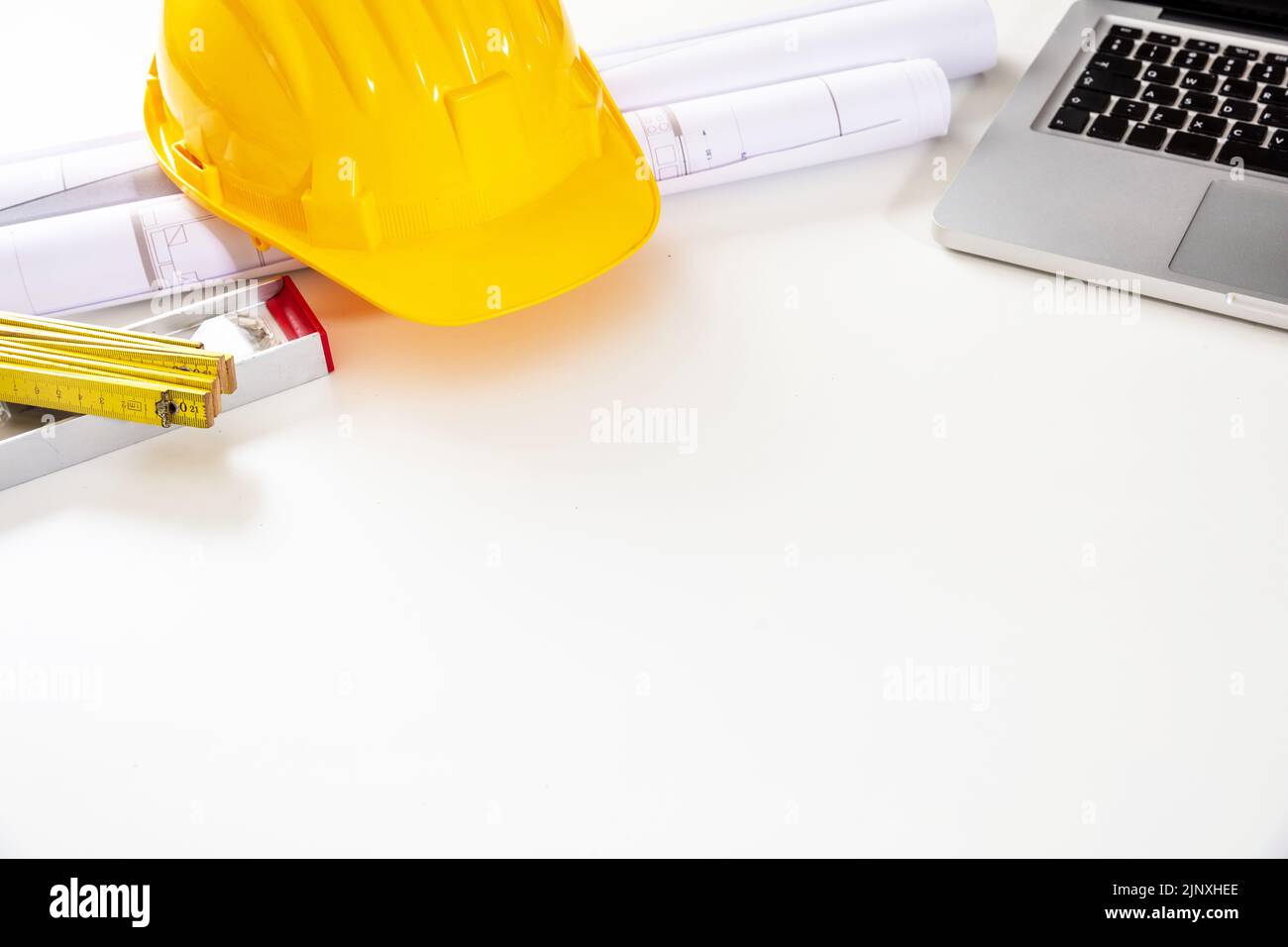 Progetto di costruzione, ufficio tecnico architetto. Elmetto di sicurezza, piani di costruzione e laptop su bianco, spazio copia Foto Stock