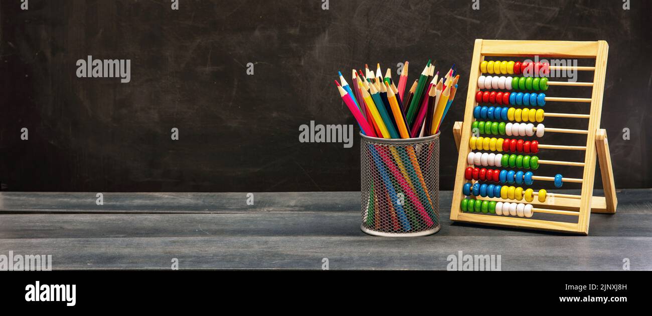 Torna al modello scolastico. Matite colorate e Abaco su scrivania in legno blu, sfondo lavagna, spazio copia Foto Stock