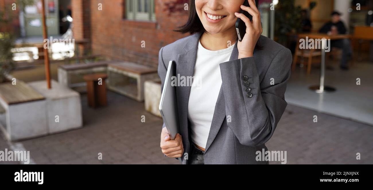 Giovane donna d'affari che indossa tuta parlare al telefono facendo una chiamata all'aperto. Foto Stock