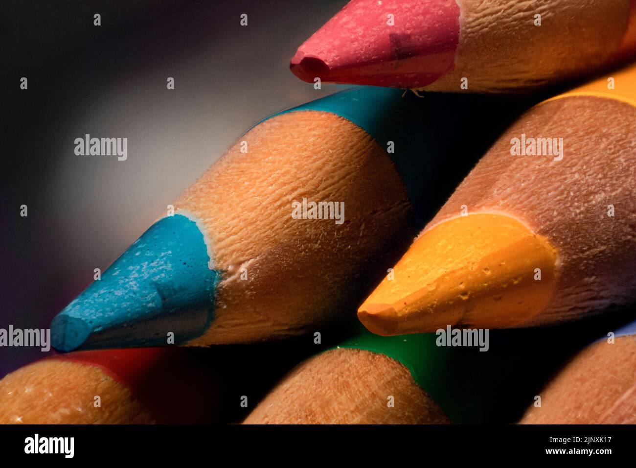 Primo piano estremo della punta affilata di matite blu, rosa, gialle e verdi, scuola e forniture d'arte Foto Stock