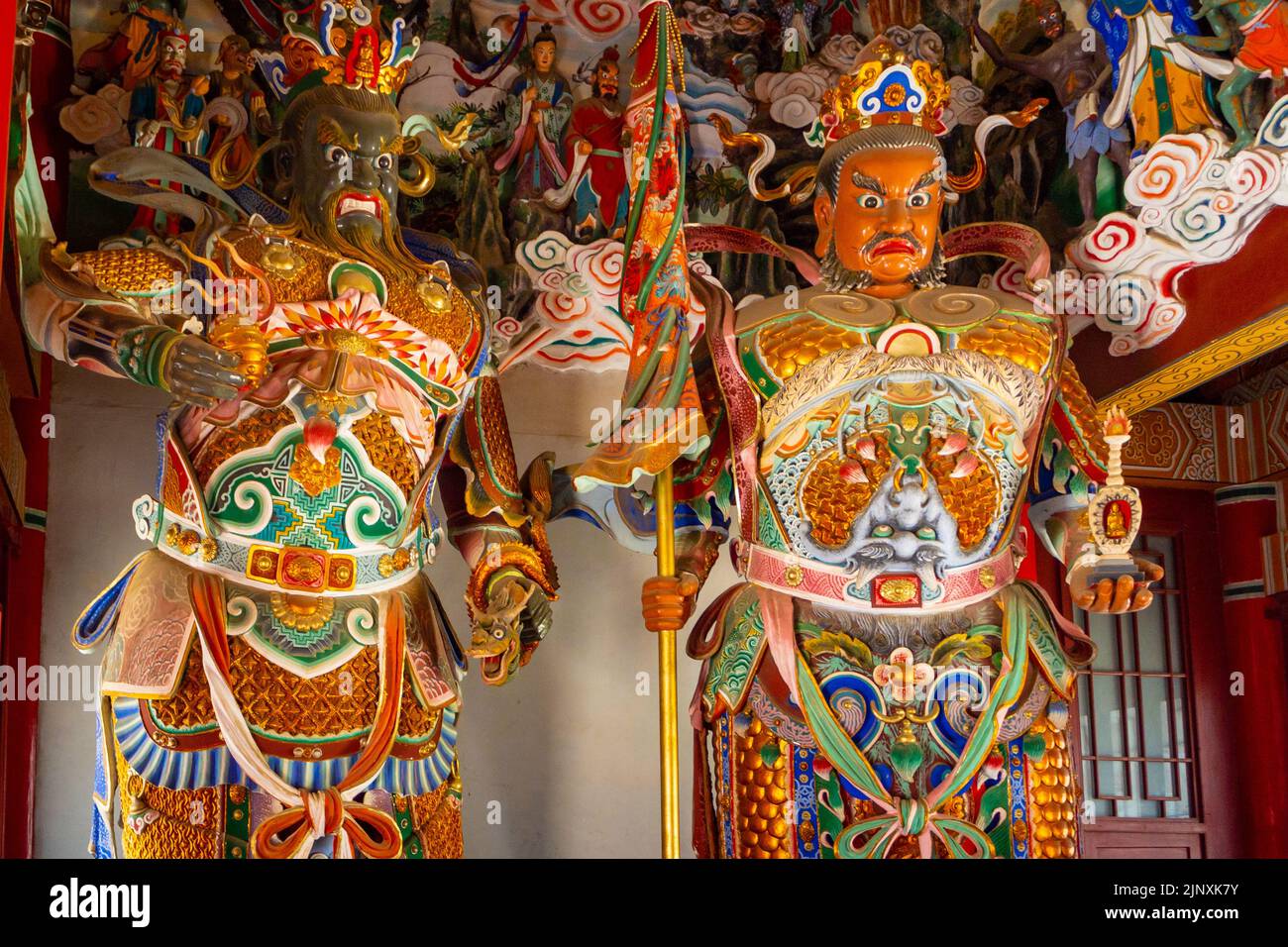 Due statue religiose tradizionali cinesi all'interno di un tempio. Le sculture o i simboli hanno abiti multicolore. Foto Stock
