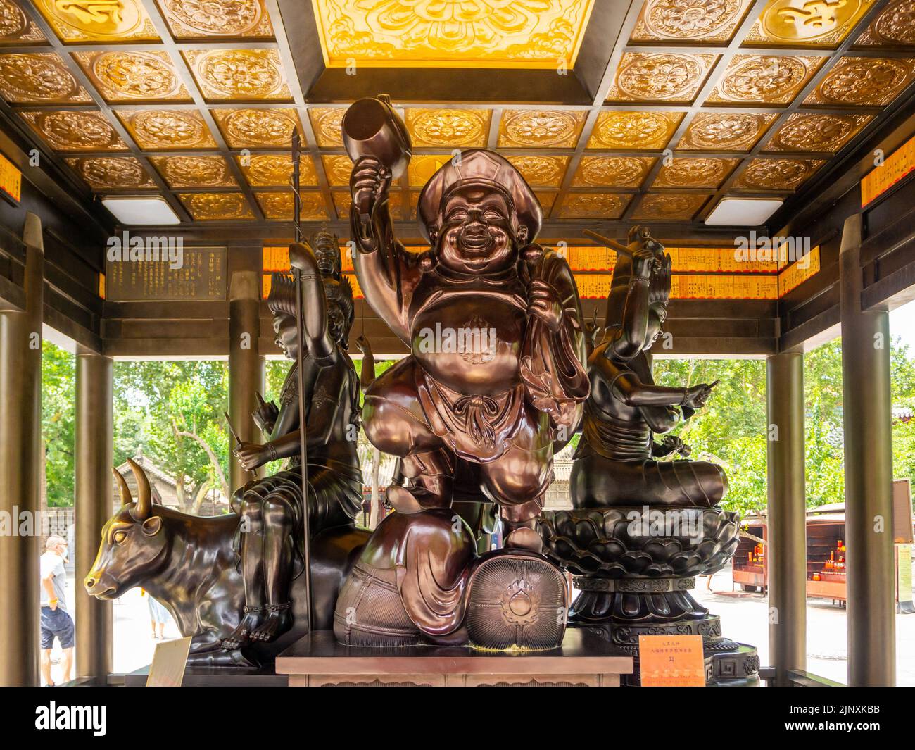 Una scultura o statua religiosa tradizionale si trova sotto un gazebo in un parco pubblico. Il simbolo fa parte della cultura cinese Foto Stock