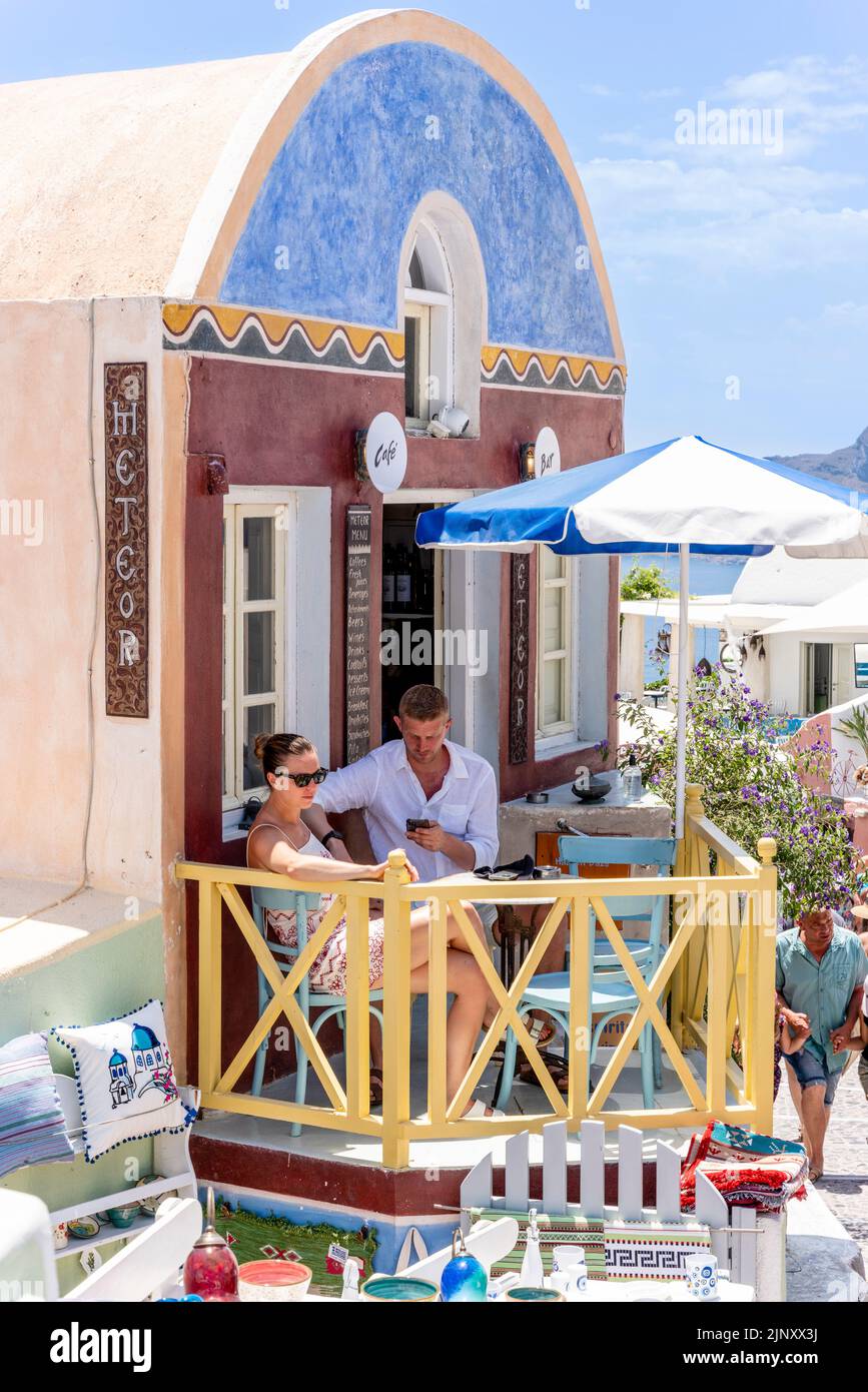 Una coppia si siede con un drink sulla piccola Terrazza di Un caffè nella città di Oia, Santorini, Isole Greche, Grecia. Foto Stock