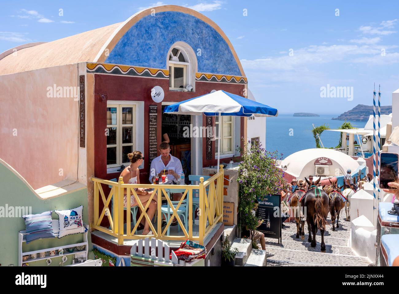 Una coppia si siede con un drink sulla piccola Terrazza di Un caffè nella città di Oia, Santorini, Isole Greche, Grecia. Foto Stock