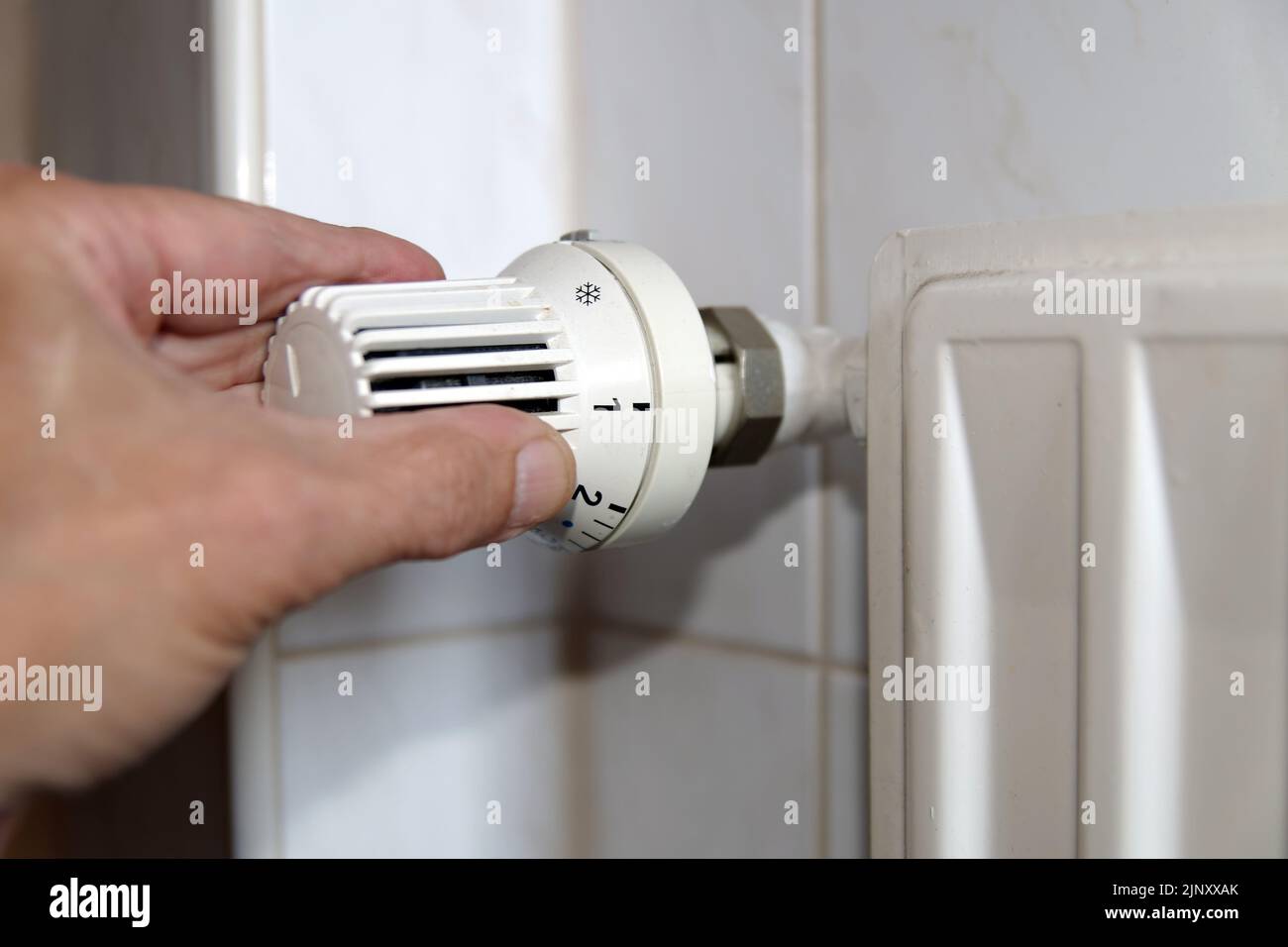 Mancanza di gas e aumento dei costi di riscaldamento: Mano su un termostato radiatore Foto Stock