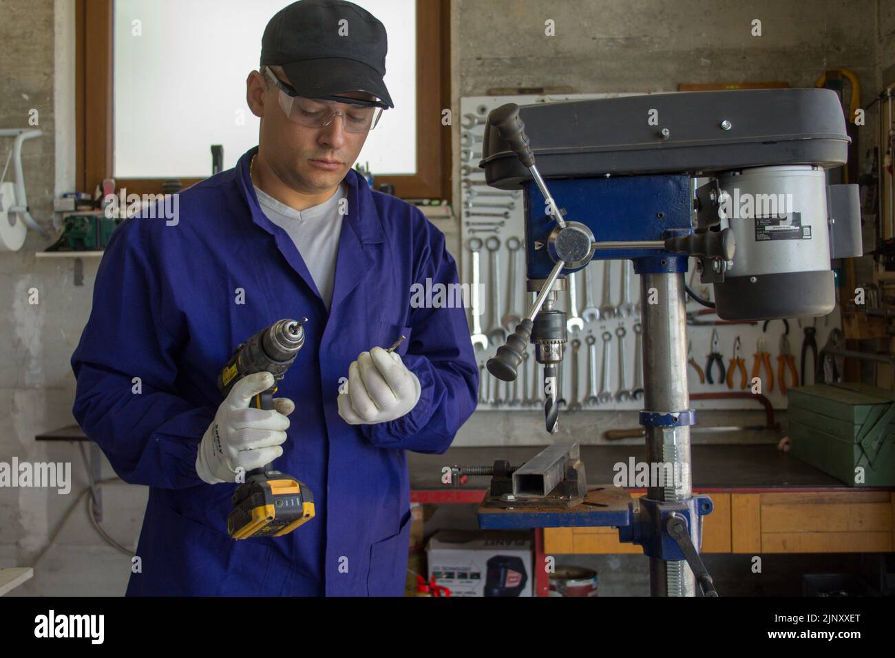 Immagine di un fabbro nella sua bottega che tiene un trapano e una punta rotta. Fatelo da soli e il duro problema della lavorazione dei metalli Foto Stock