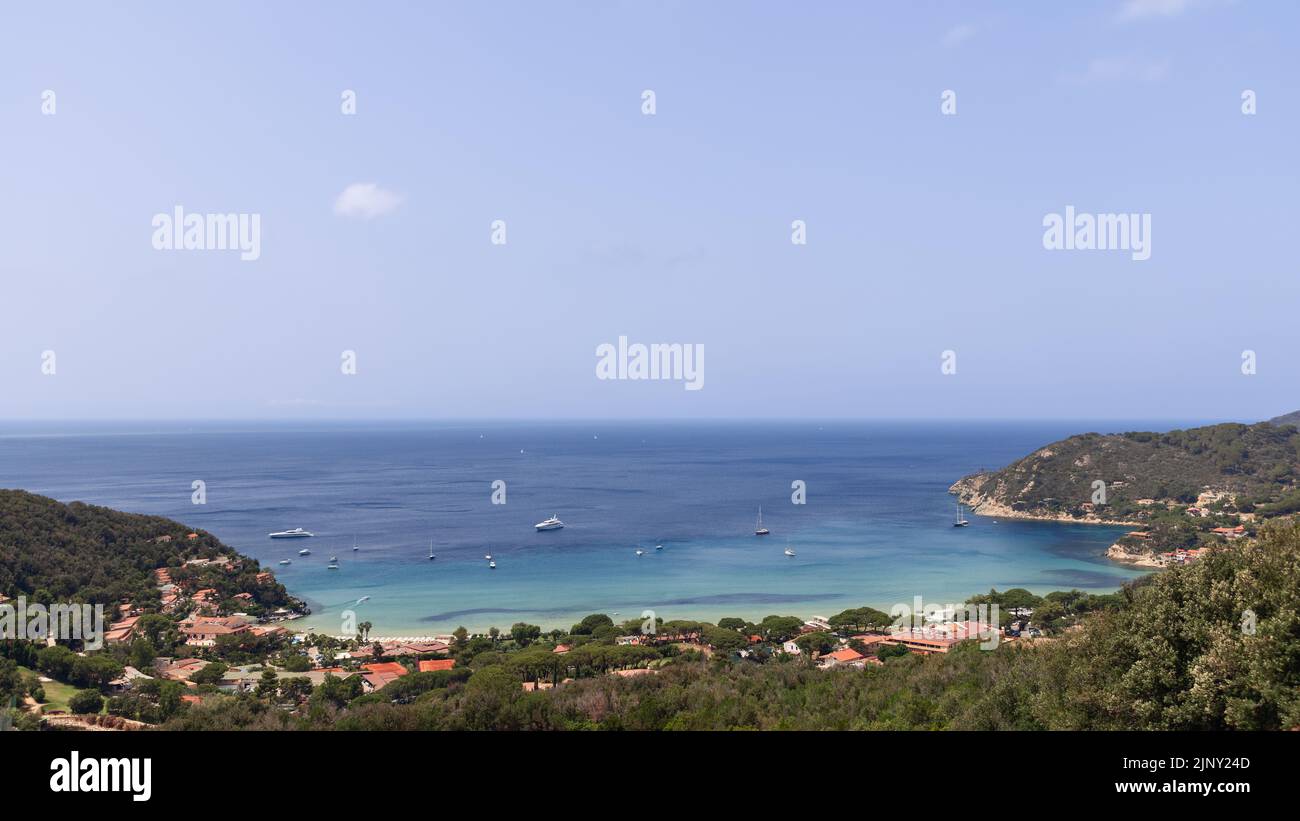 Tipica baia della costa nord dell'isola d'Elba con basse colline ricoperte di fitta foresta, acqua color smeraldo in piccole e accoglienti baie e spiagge di sabbia bianca Foto Stock