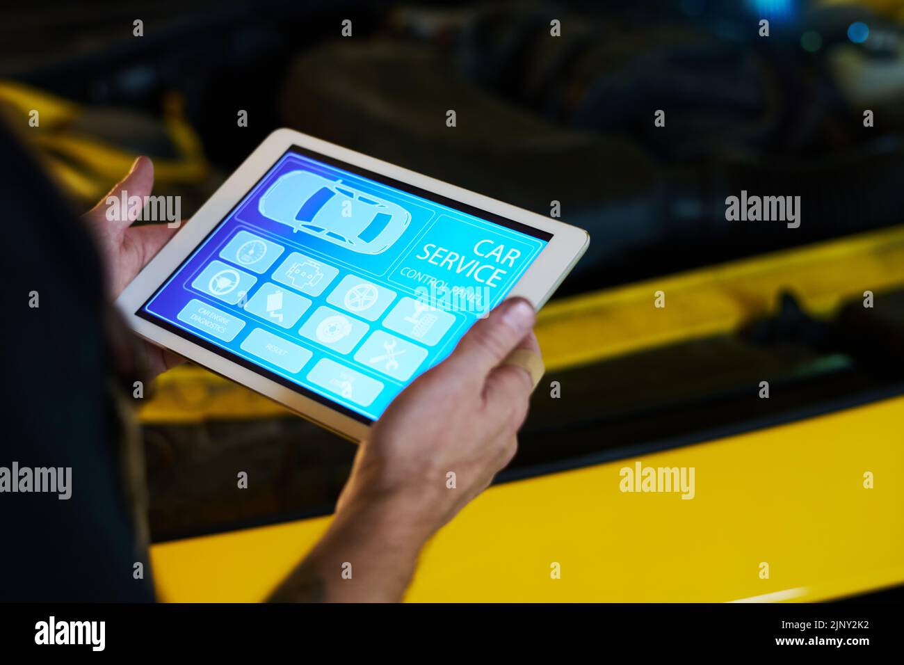 Mani del meccanico maschile del servizio di manutenzione tenere tablet con home page con icone sullo schermo mentre si è in piedi in auto Foto Stock