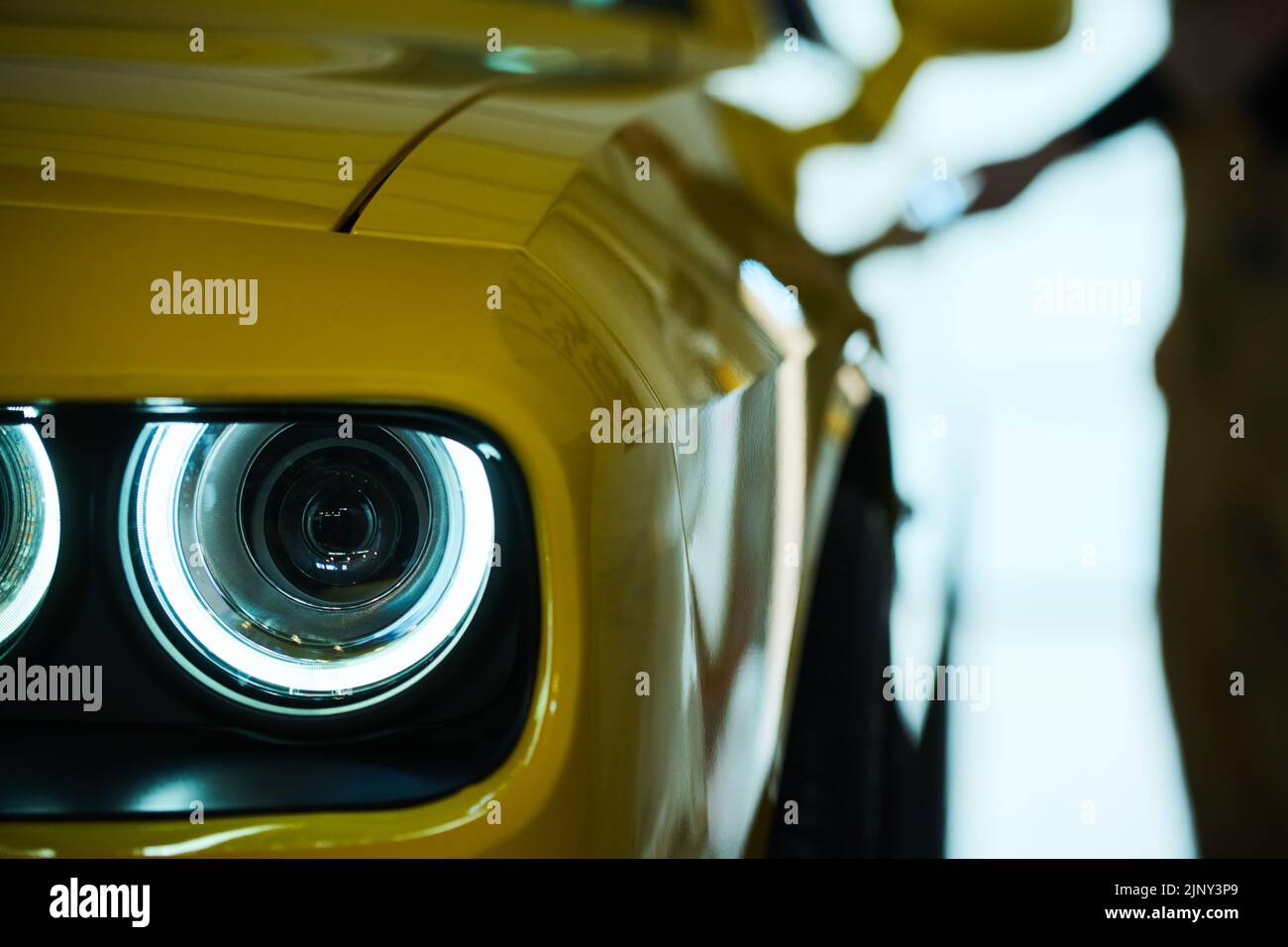 Faro sulla parte anteriore di una lussuosa auto elettrica di colore giallo in piedi sul parcheggio, in garage o in officina dopo la riparazione Foto Stock