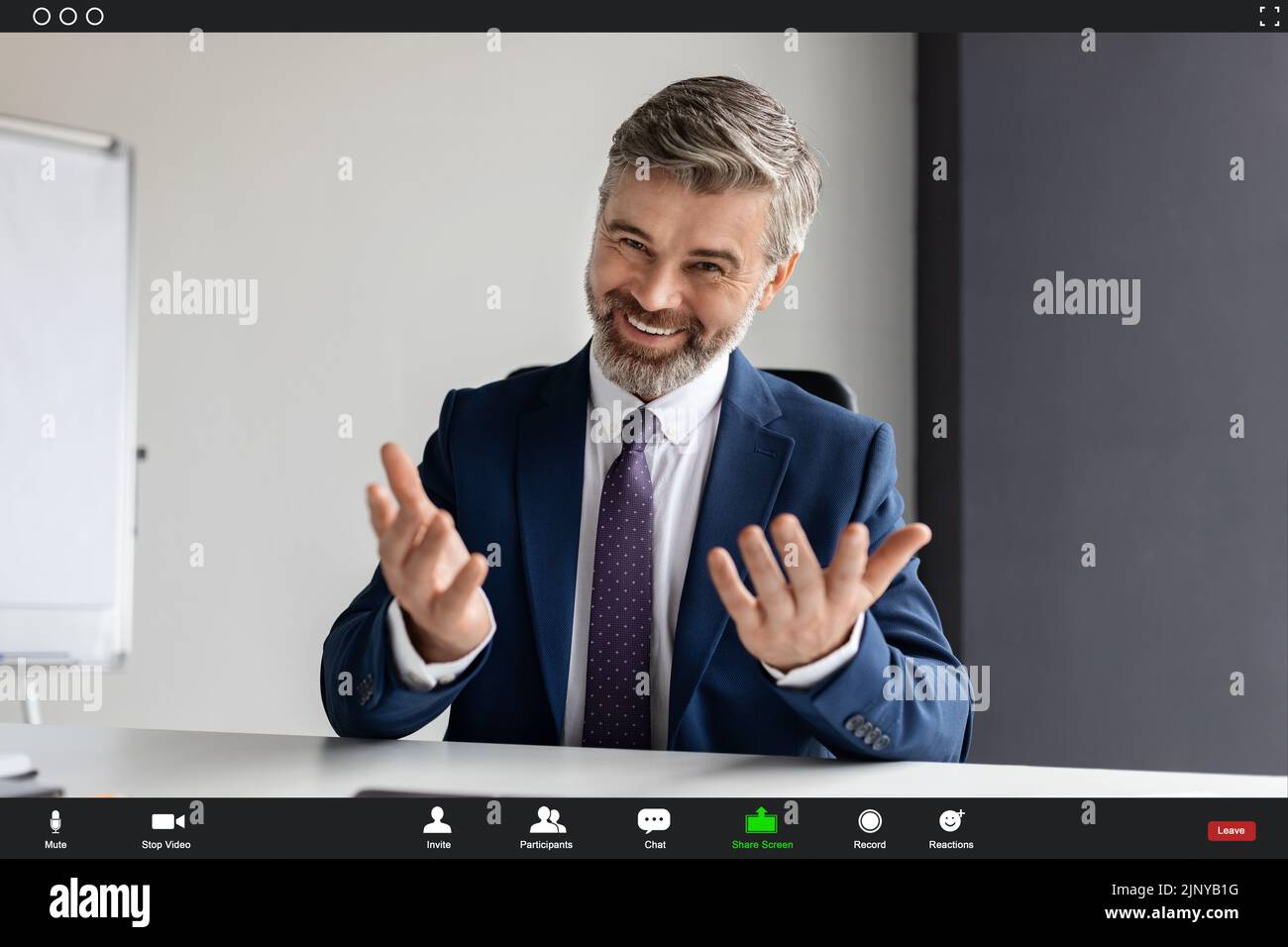 Bell'uomo d'affari maturo che effettua la videochiamata dall'ufficio, schermata POV Foto Stock