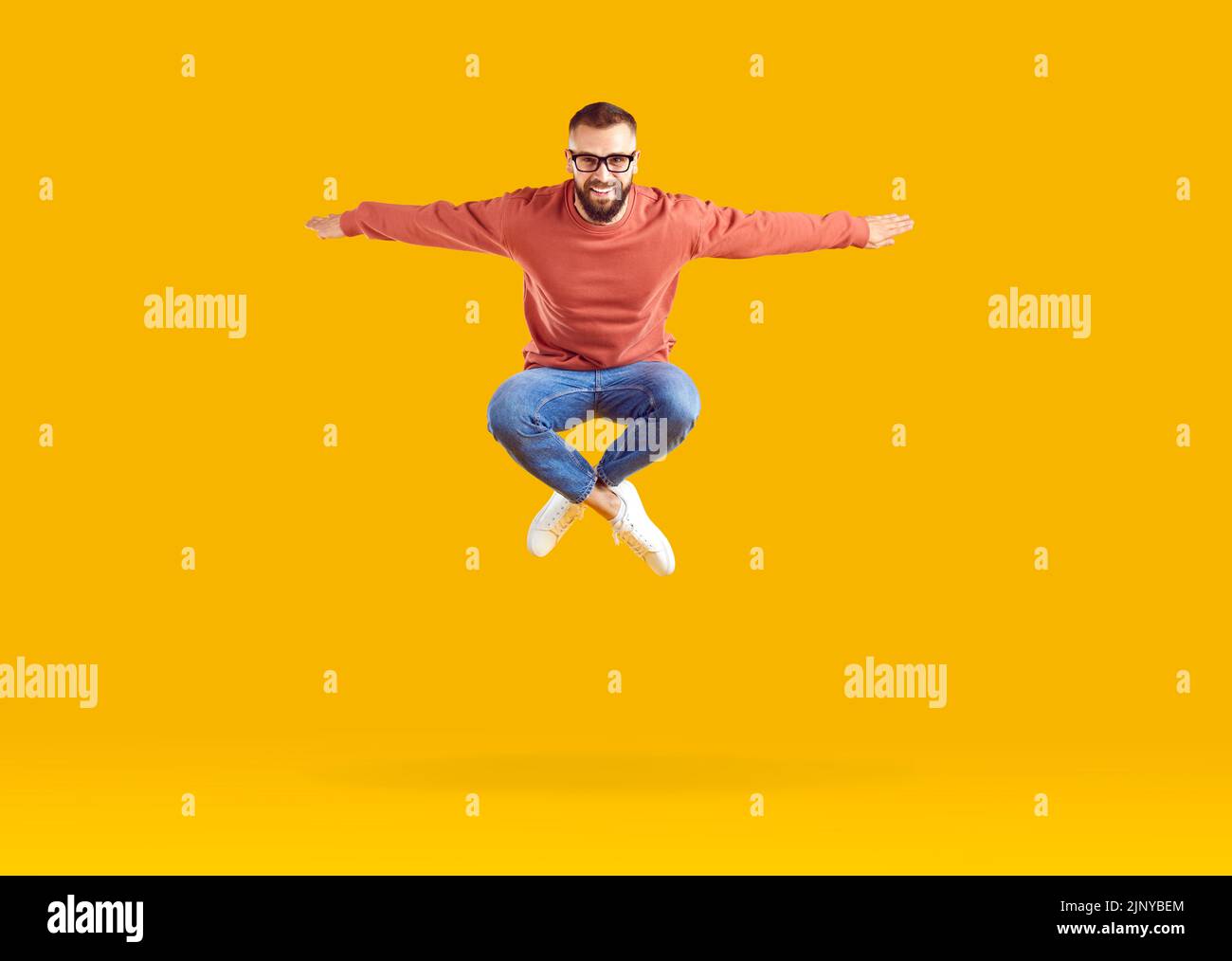 Eccitato giovane uomo caucasico salto celebrando il successo in posa in studio arancione Foto Stock