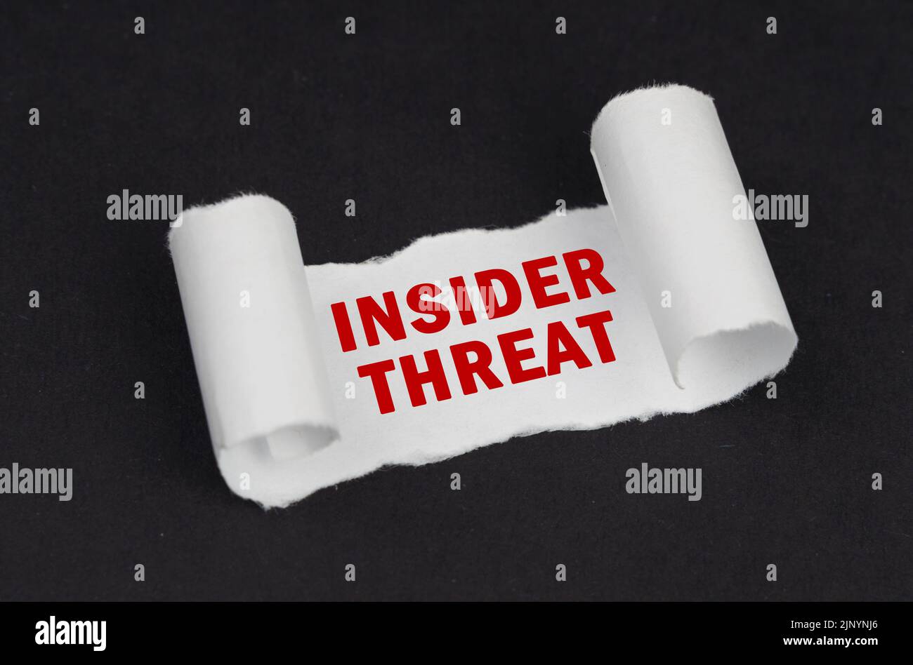 Su una superficie nera si trova una carta bianca ritorta con l'iscrizione - Insider Threat. Concetto aziendale. Foto Stock