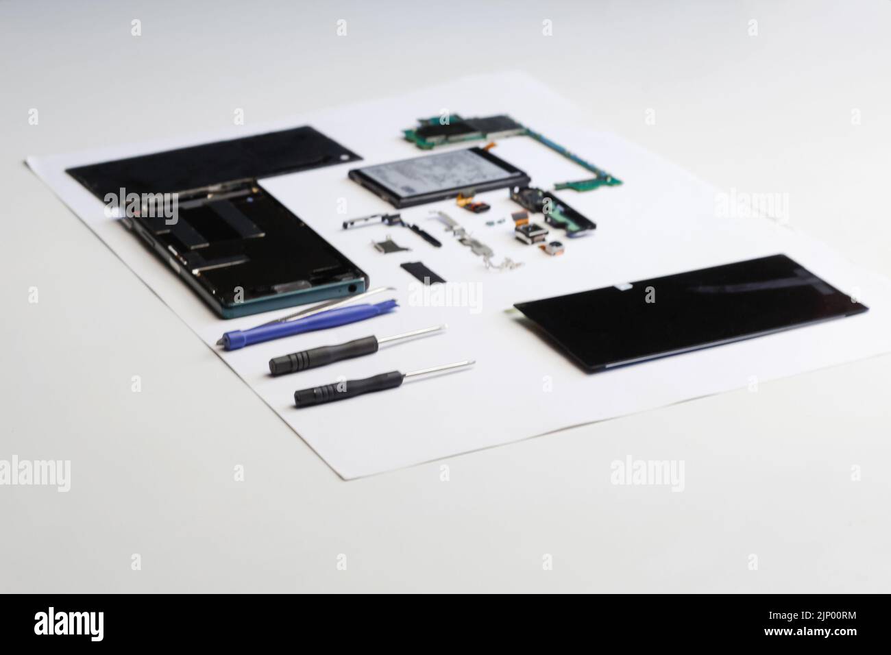 Defocus riparazione elettronica. Tecnico che ripara il circuito stampato elettronico con saldatore. Ingegnere smontaggio componenti smartphone e guasto Foto Stock