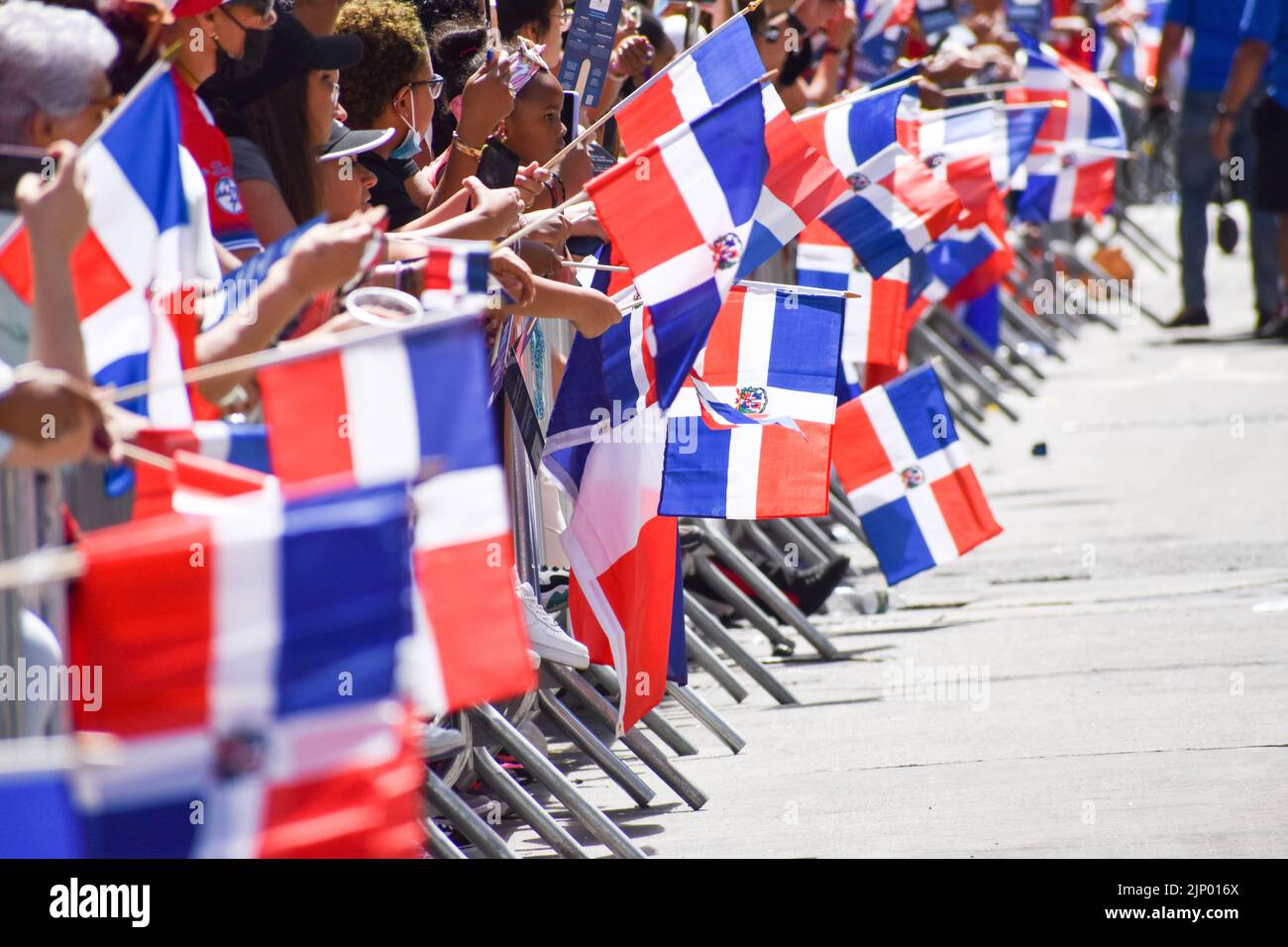 I newyorkesi di tutte le età stanno tenendo bandiere dominicane durante la parata domenicana di giorno sulla Sixth Avenue a New York City. Foto Stock