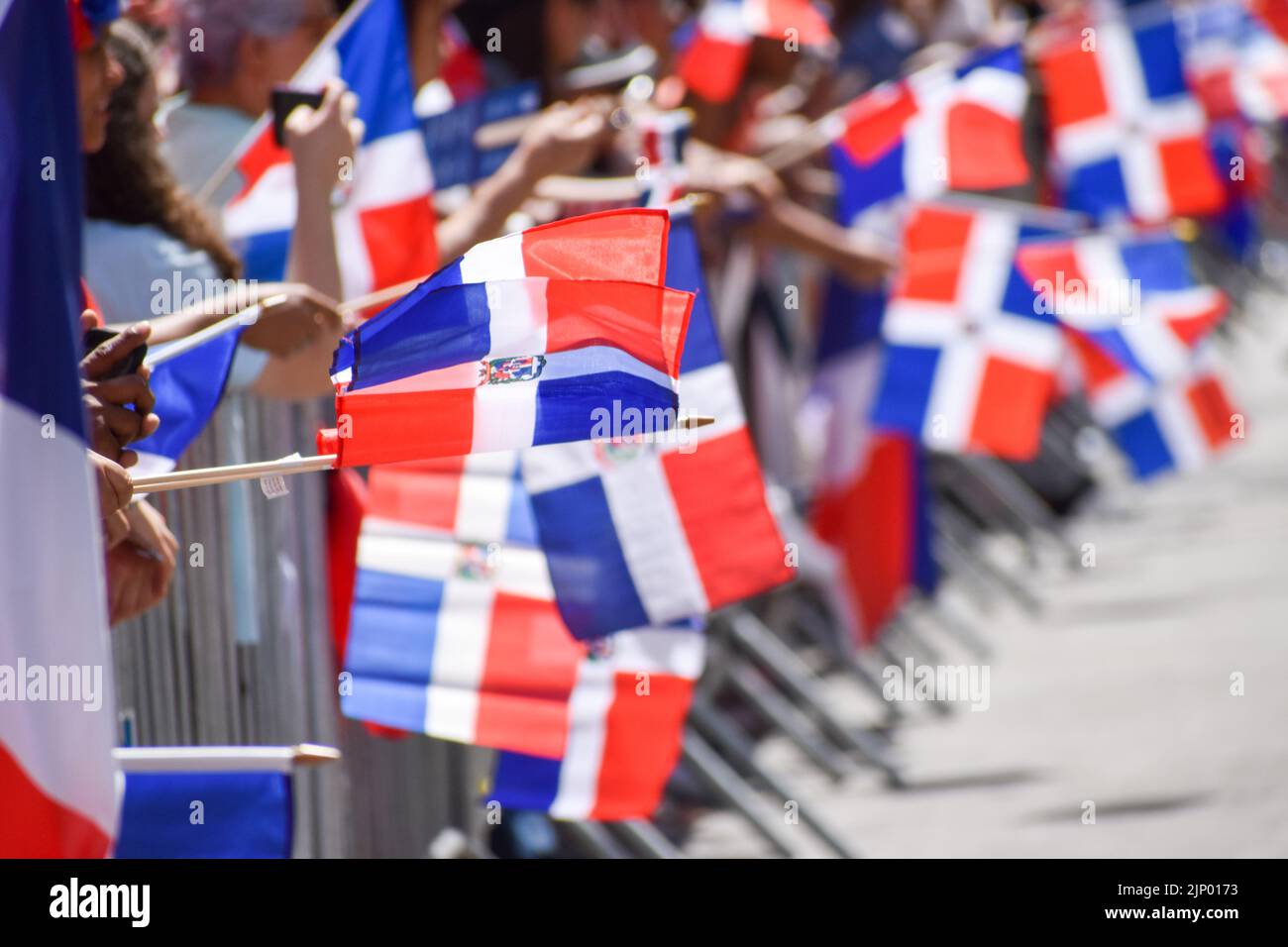 I newyorkesi di tutte le età stanno tenendo bandiere dominicane durante la parata domenicana di giorno sulla Sixth Avenue a New York City. Foto Stock