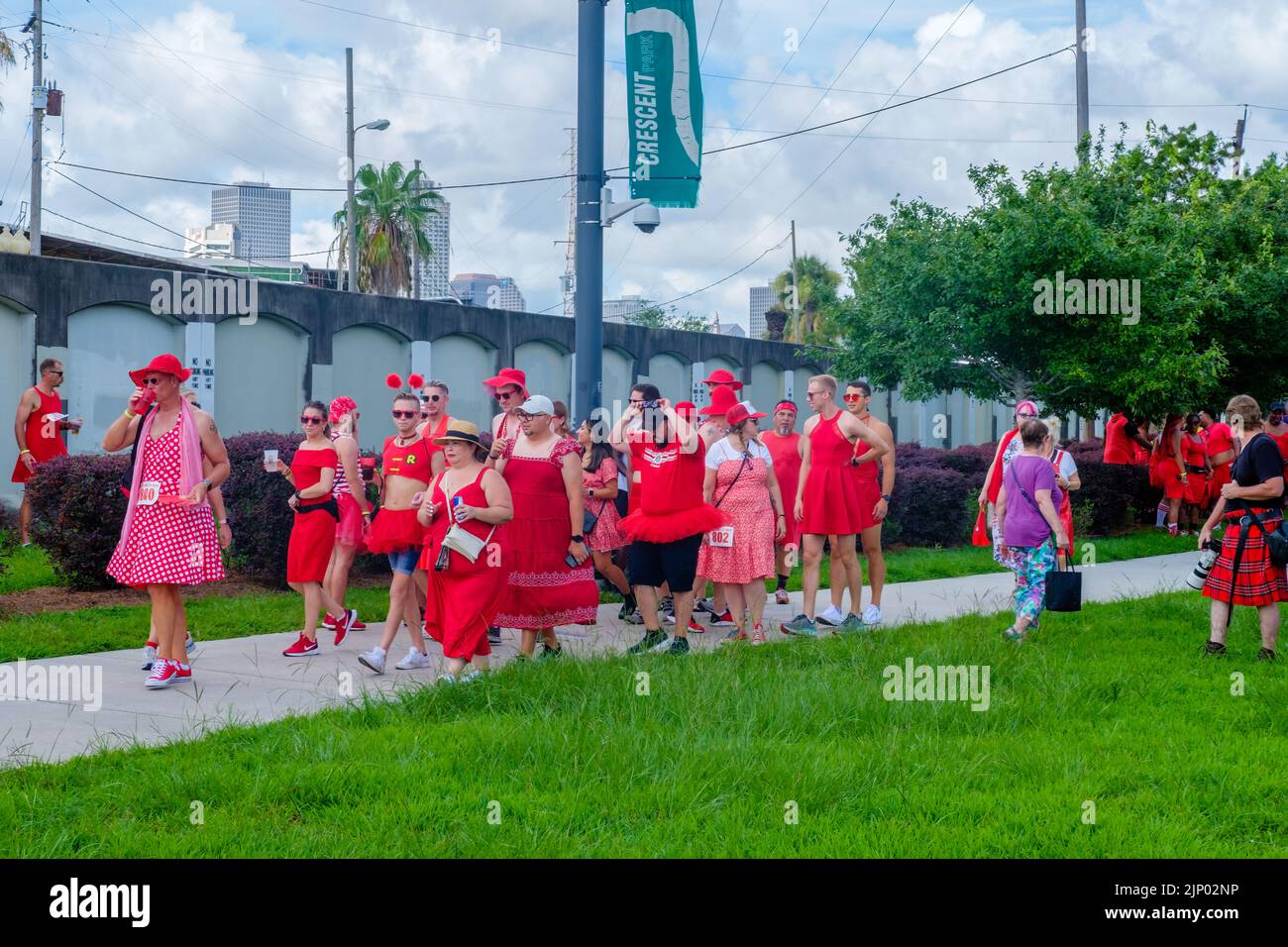 NEW ORLEANS, LA, USA - 13 AGOSTO 2022: La folla in costume cammina verso Crescent Park per l'inizio dell'annuale Red Dress Run Foto Stock