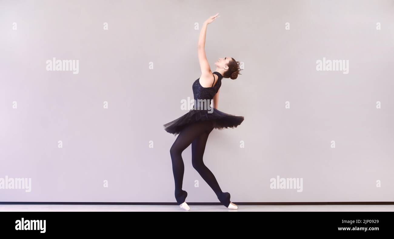 ballerina aggraziata in abito di cigno nero. Ballerina giovane prima dello spettacolo in tutu nero, studio di danza classica, spazio copia Foto Stock