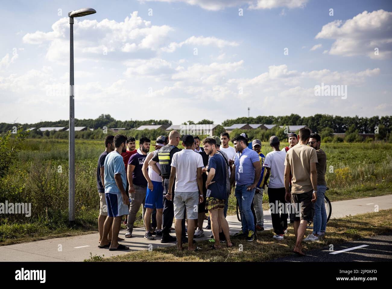 2022-08-14 17:23:19:19 ter APEL - Un ufficiale di polizia parla con un gruppo di richiedenti asilo presso il centro di accoglienza sovraffollato a Groningen dopo aver separato le parti in lite. Poiché la catena dell’asilo è nascosta, è rimasta irrequieta da mesi a Ter Apel. I titolari dello status, che possono soggiornare nei Paesi Bassi, non possono ottenere una casa e sono quindi costretti a continuare a vivere in un centro per i richiedenti asilo. Di conseguenza, non c'è posto per i nuovi richiedenti asilo e le persone a Ter Apel sono costrette a dormire all'aria aperta. ANP RAMON VAN FLYMEN olanda fuori - belgio fuori Foto Stock
