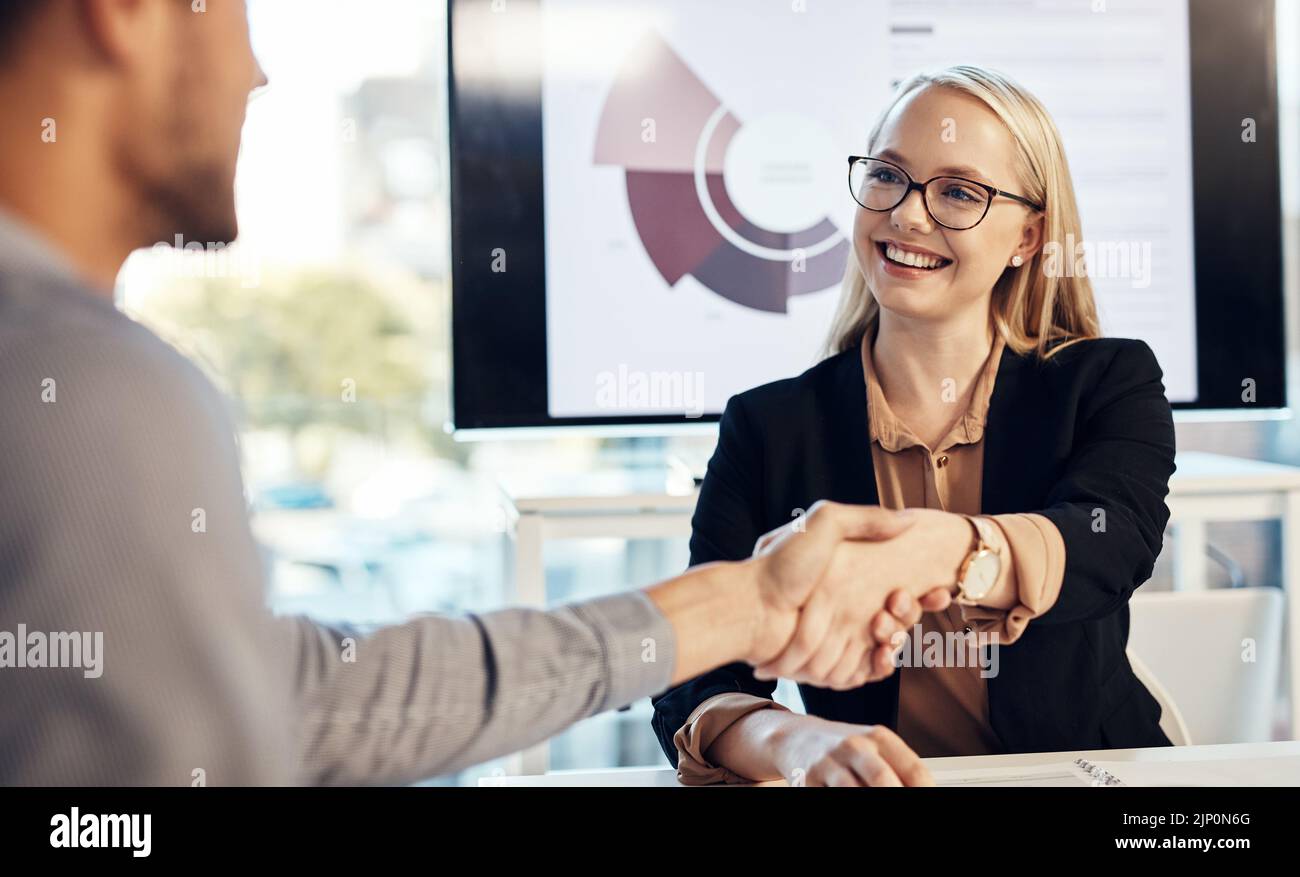 Mantenga lo slancio andare. Una giovane donna d'affari e un uomo d'affari che scuotono le mani durante una riunione in un ufficio moderno. Foto Stock