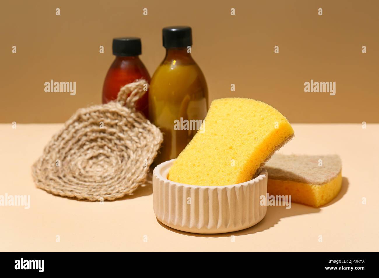 Spugne e bottiglie per la casa su sfondo colorato Foto Stock