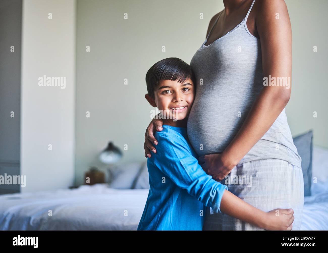 Il mio cuore ha spazio per un altro. Ritratto corto di un adorabile ragazzino in piedi contro il ventre incinta delle madri. Foto Stock