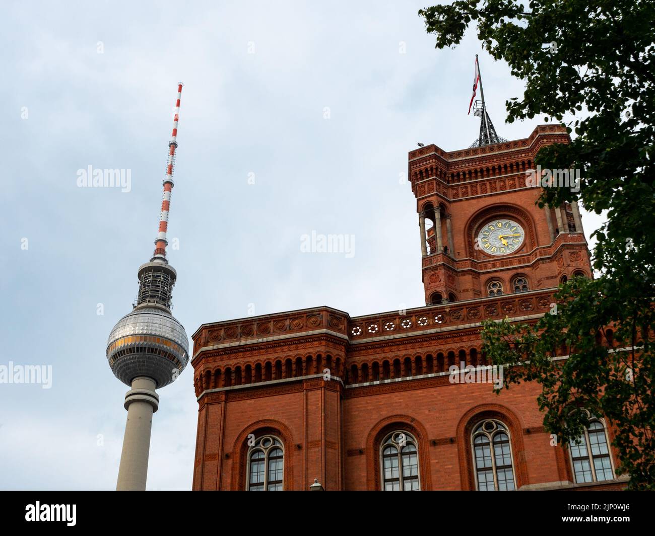 La famosa torre televisiva di Berlino e il municipio rosso l'uno accanto all'altro. Vista ad angolo basso delle attrazioni turistiche. Famosi punti di riferimento in Germania. Foto Stock