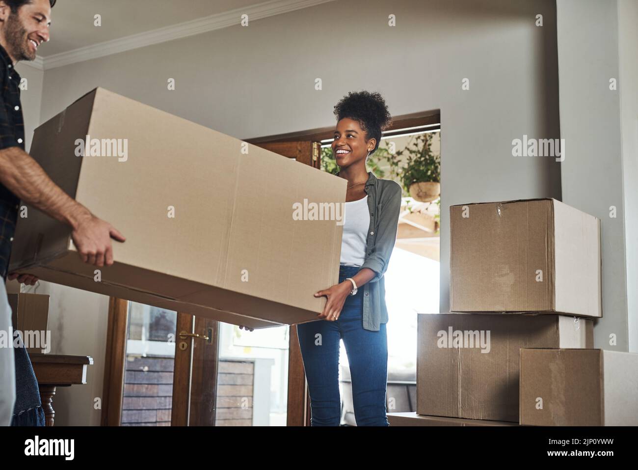 Coppia del proprietario domestico che sposta le scatole in nuova sede che osserva allegro o eccitato all'interno della loro casa o spazio di soggiorno del bene immobile. Sposato per la prima volta Foto Stock