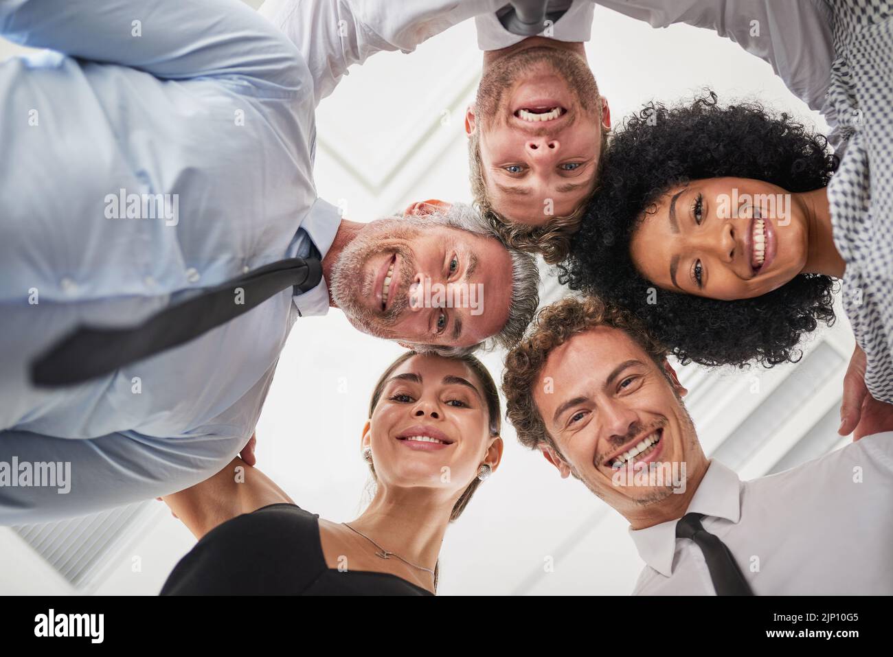 Erano un team di colleghi molto stretti. Ritratto ad angolo basso di un gruppo di uomini d'affari accoccolati insieme in solidarietà. Foto Stock