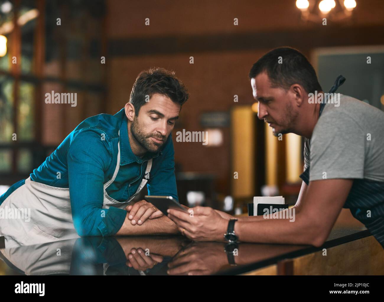 Questo è il numero di svendite vendute negli ultimi mesi. Due giovani lavoratori che discutono di affari insieme su un cellulare all'interno di una birreria di birra durante Foto Stock