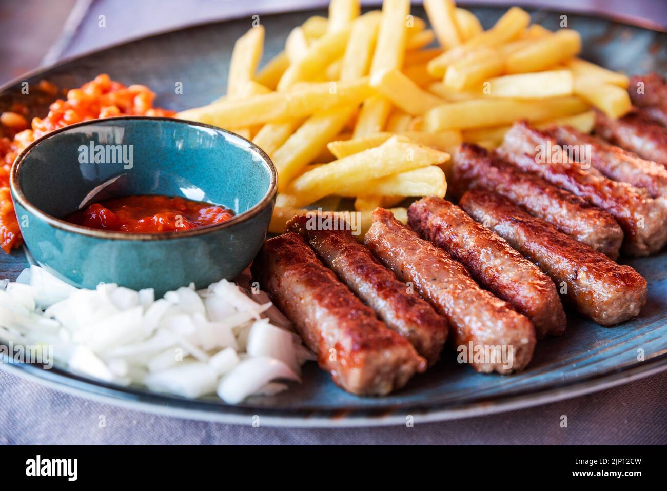 Porec, Croazia. Cevapcici arrotolati tradizionali fritti, polpettine di carne macinata con patatine fritte e ketchup serviti al ristorante. Paesi specifici dei Balcani Foto Stock