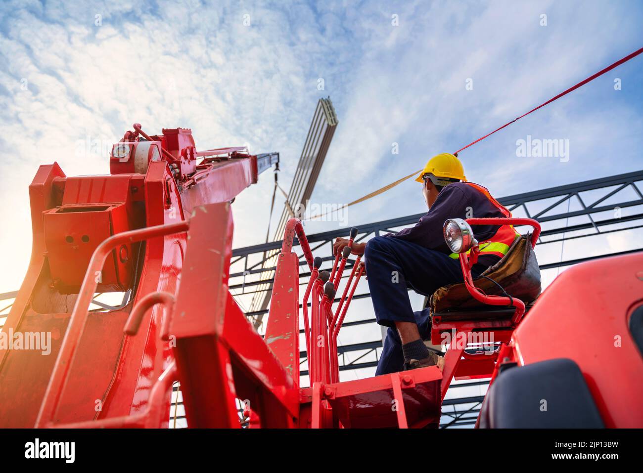 Asian Crane driver, Crane driver sedersi un top in una cabina gru mobile e lavorare sollevando il tetto o PU espanso lamiera del tetto in cantiere. Foto Stock