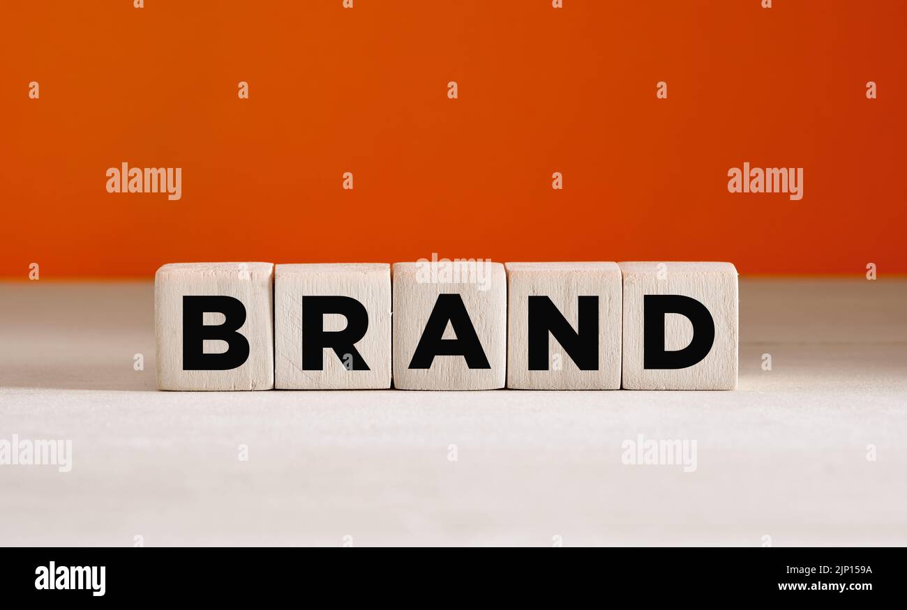 Il marchio di parola su cubi di legno su sfondo arancione con spazio di copia. Identità del marchio o concetto di consapevolezza. Foto Stock