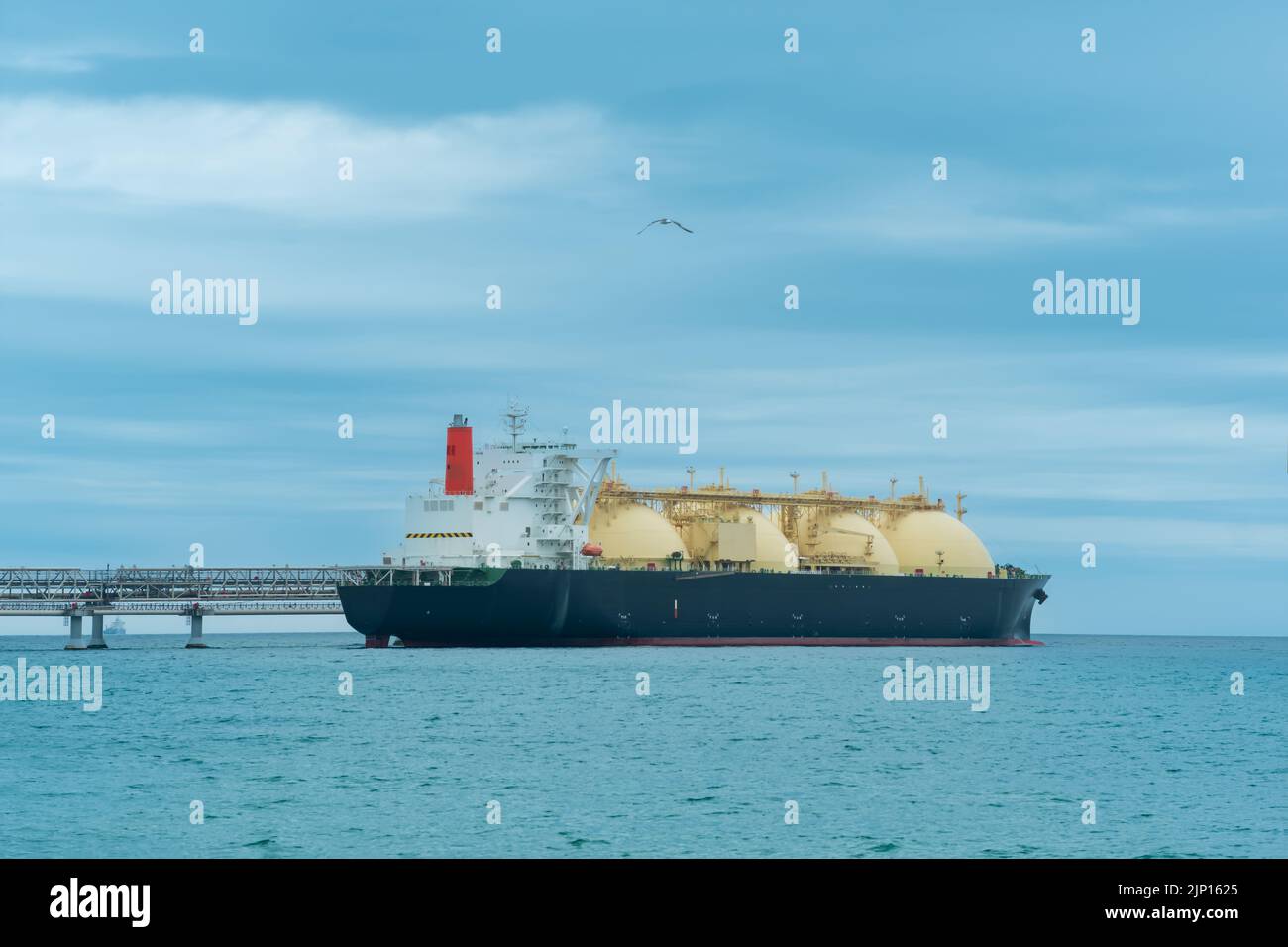 Nave cisterna per trasporto di gas naturale liquefatto durante il carico presso un terminal offshore di GNL, a distanza il terminale di esportazione del petrolio è visibile in mare Foto Stock