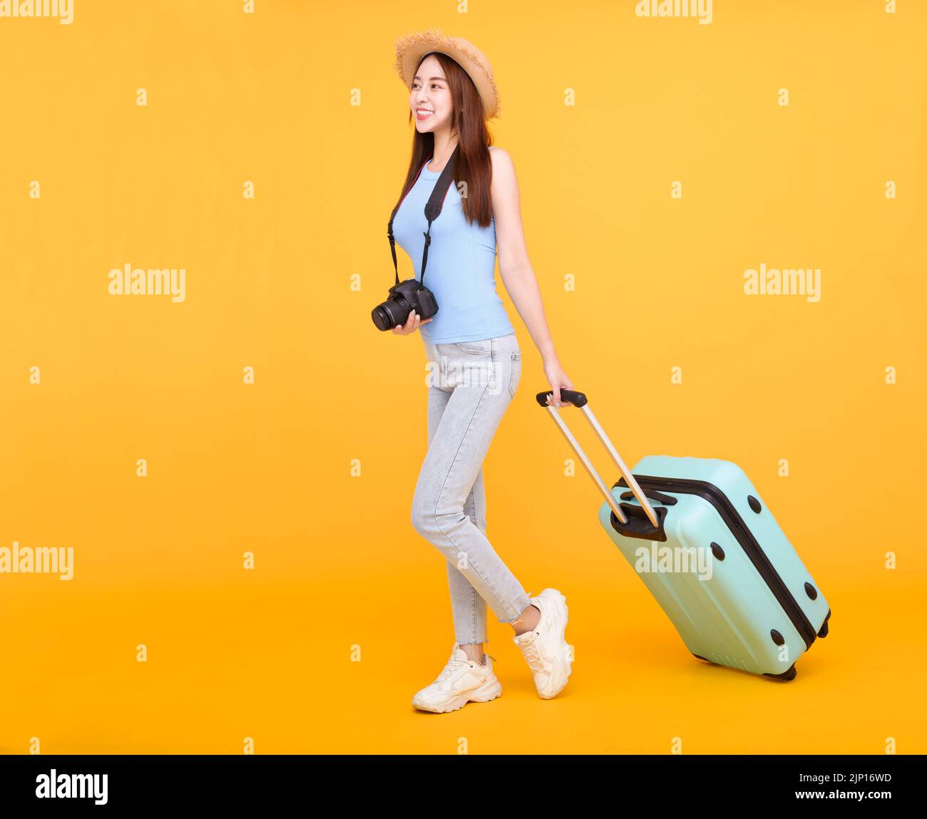 Felice giovane donna con bagagli e macchina fotografica isolato su sfondo giallo, estate, concetto di viaggio. Foto Stock