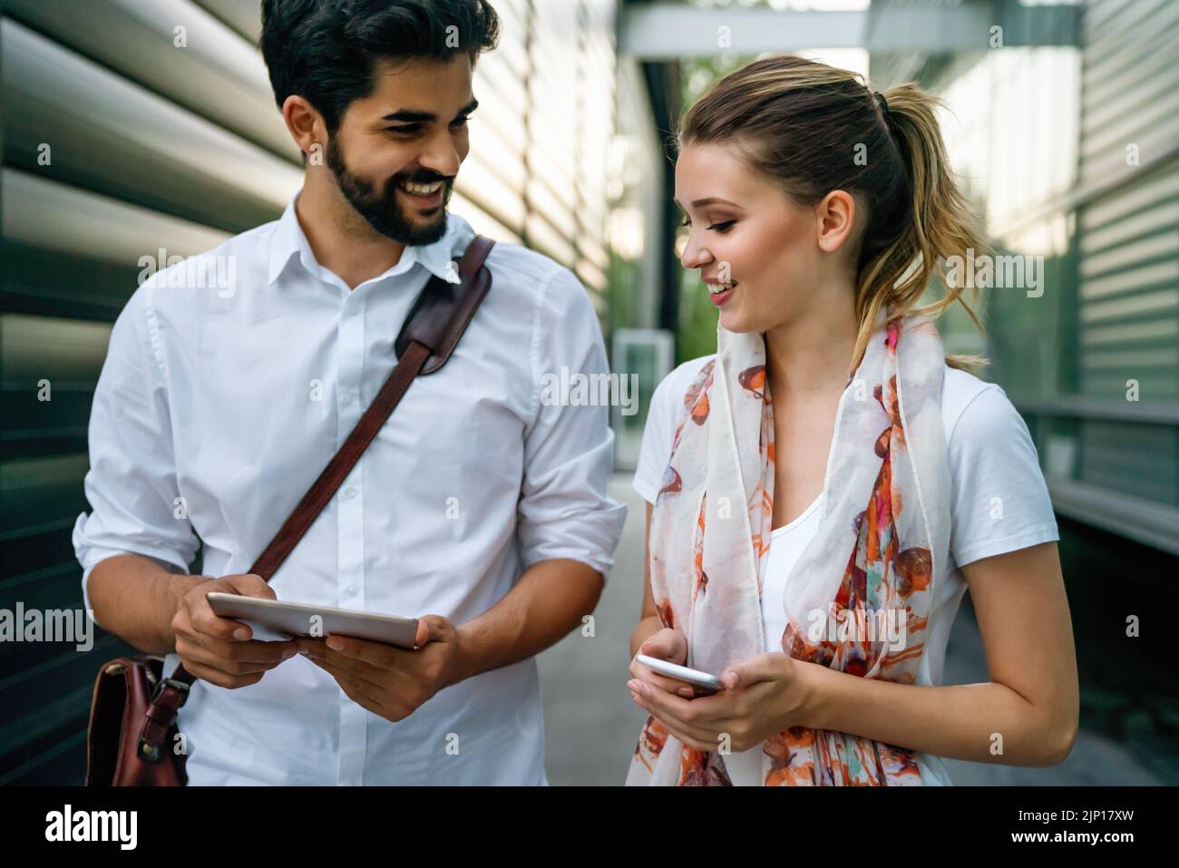 Felici le persone che lavorano all'aperto con i dispositivi digitali. Tecnologia aziendale smartphone, tablet Foto Stock