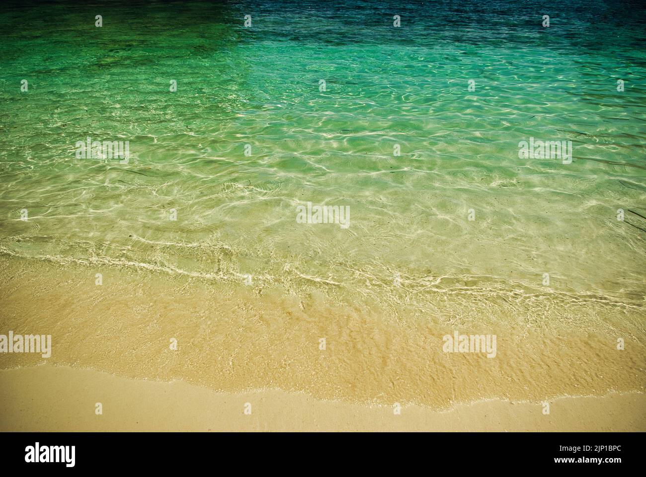 Onde di mare morbide su spiaggia sabbiosa, acque turchesi limpide, sfondo per pagine web e stampa Foto Stock