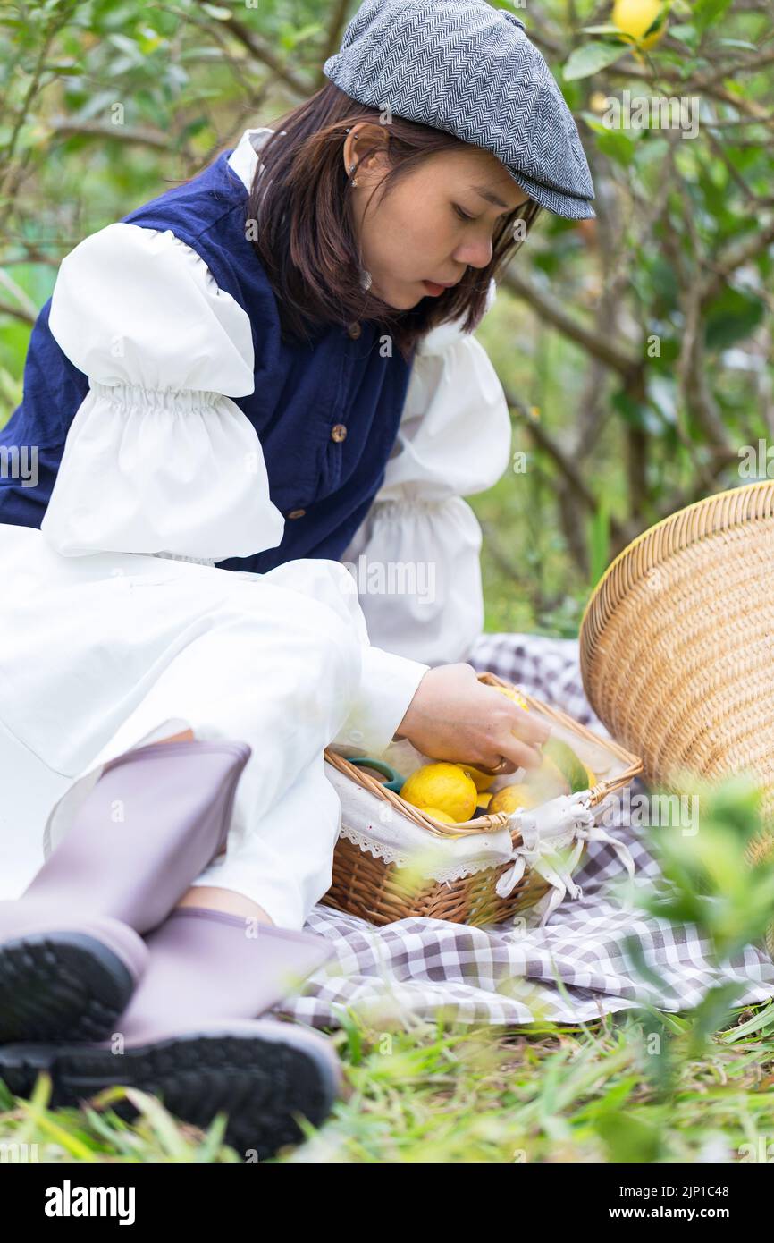 Donna asiatica lavora e viaggia in una fattoria di limoni con la moda contadina e gli accessori Foto Stock