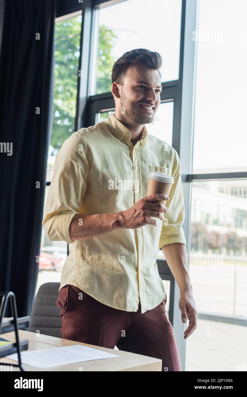 Allegro uomo d'affari in camicia che tiene la bevanda da asporto in ufficio, immagine di scorta Foto Stock