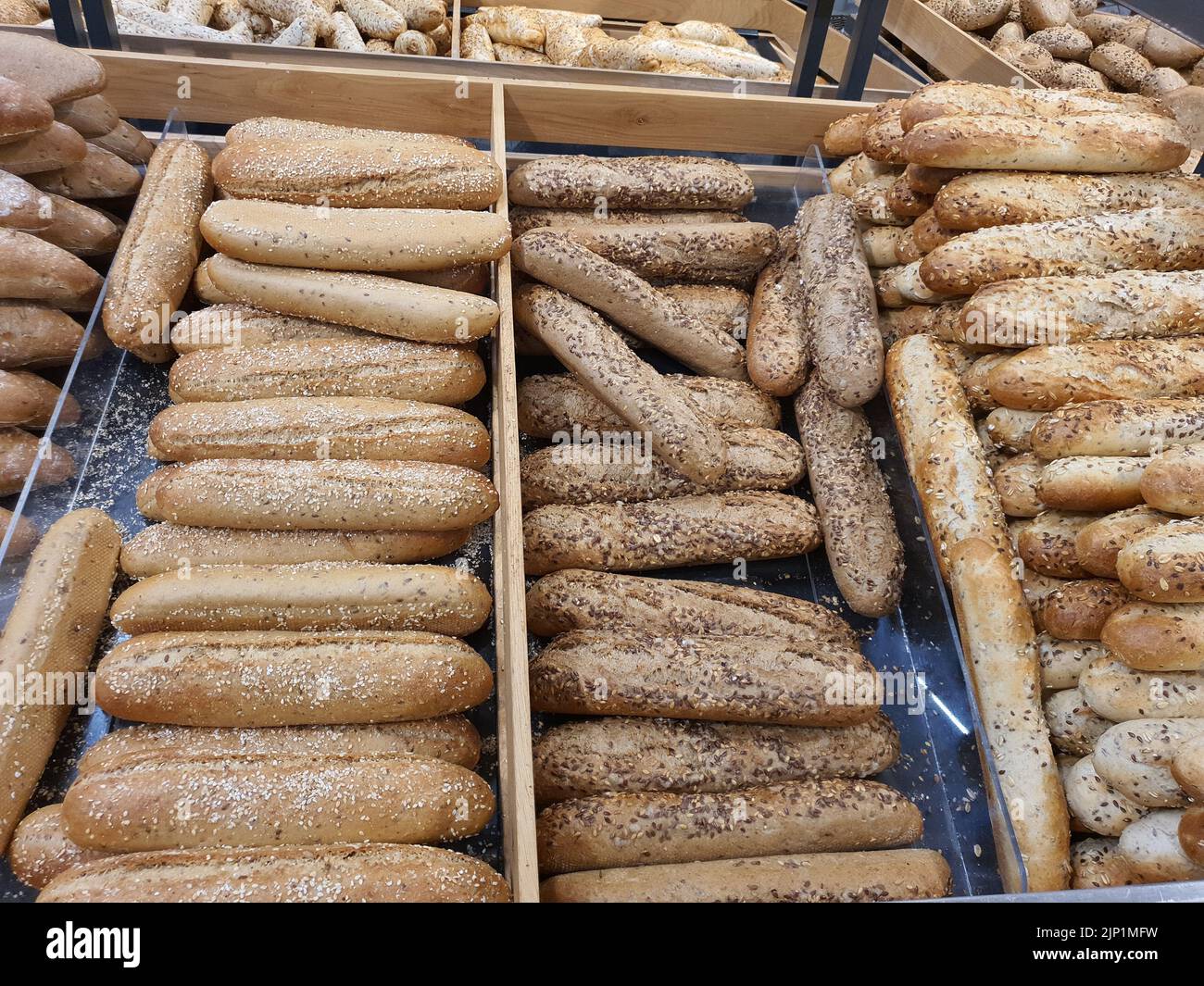 Varietà di diversi tipi di baguette francesi con semi di lino marrone e oro in panetteria o negozio di alimentari. Pane appena sfornato Foto Stock